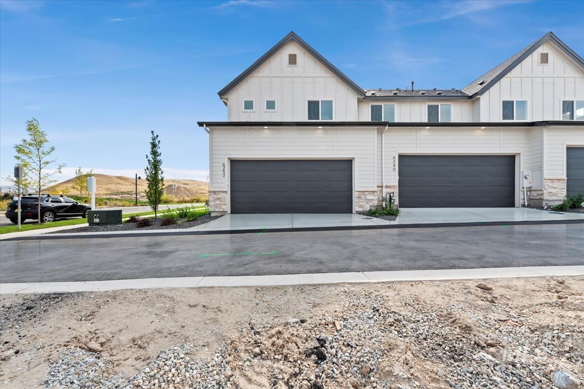 View of front facade with board and batten siding, a garage, concrete driveway, and stone siding