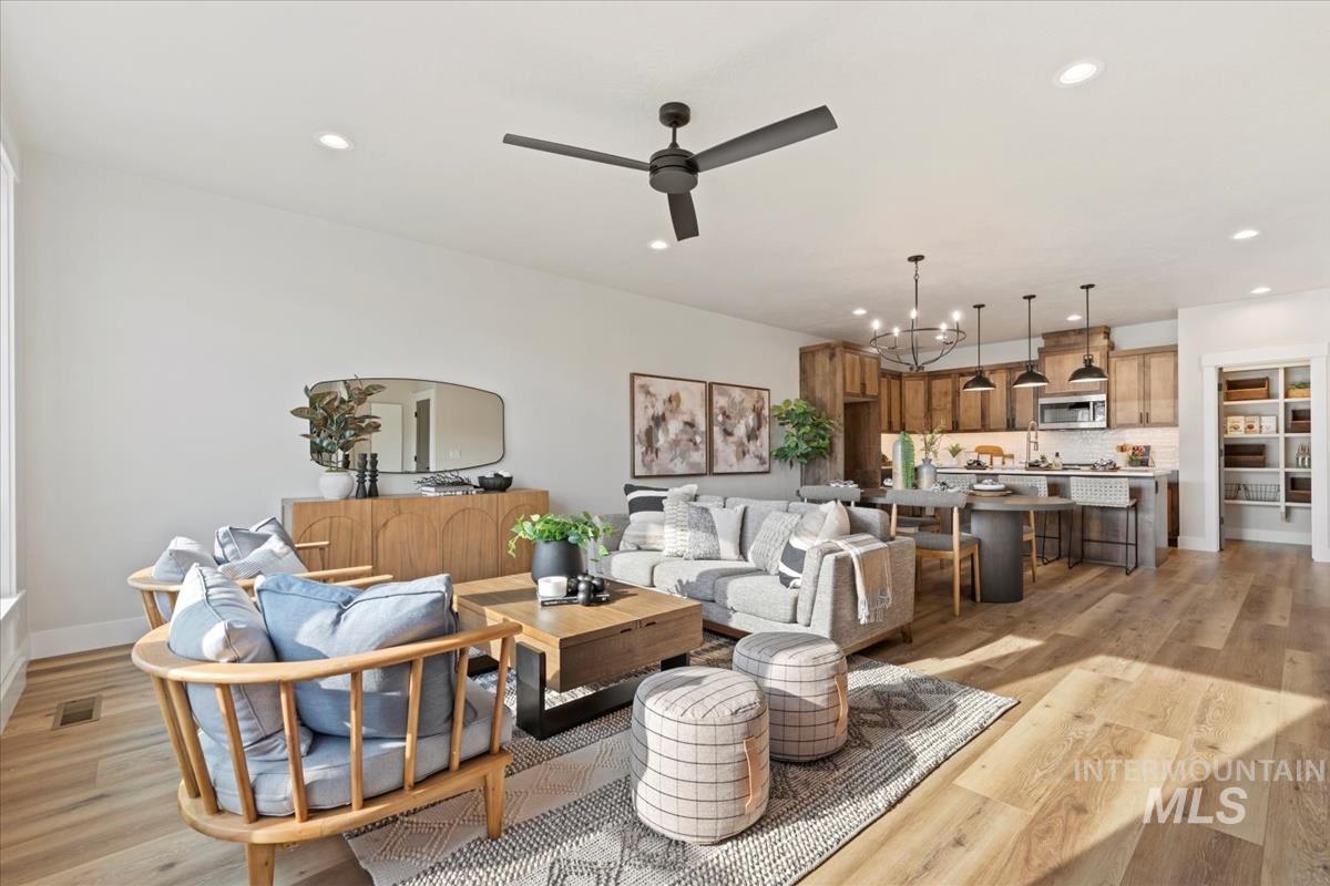 Living room with recessed lighting, a chandelier, light wood-style flooring, and a ceiling fan