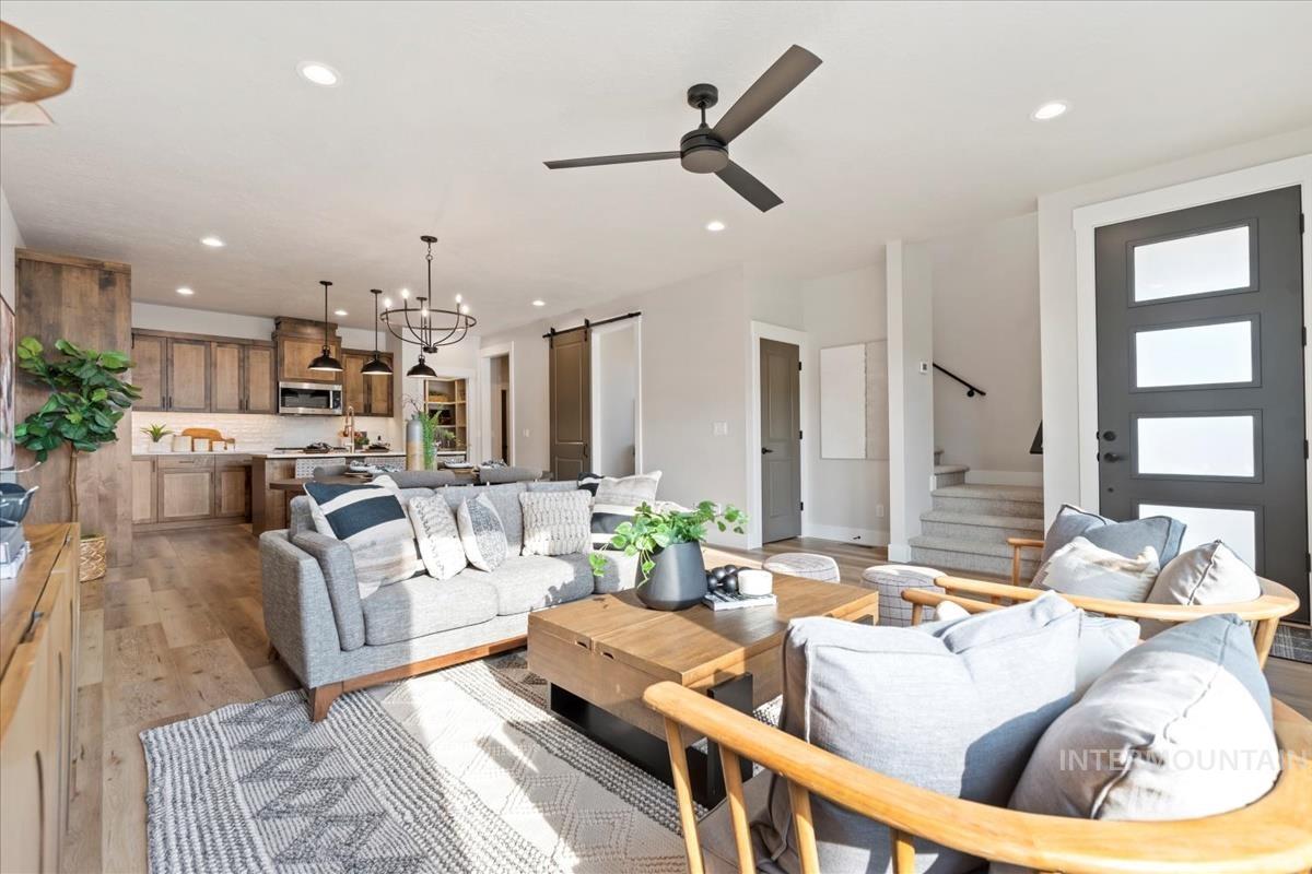 Living area featuring a barn door, stairs, light wood finished floors, a chandelier, and recessed lighting