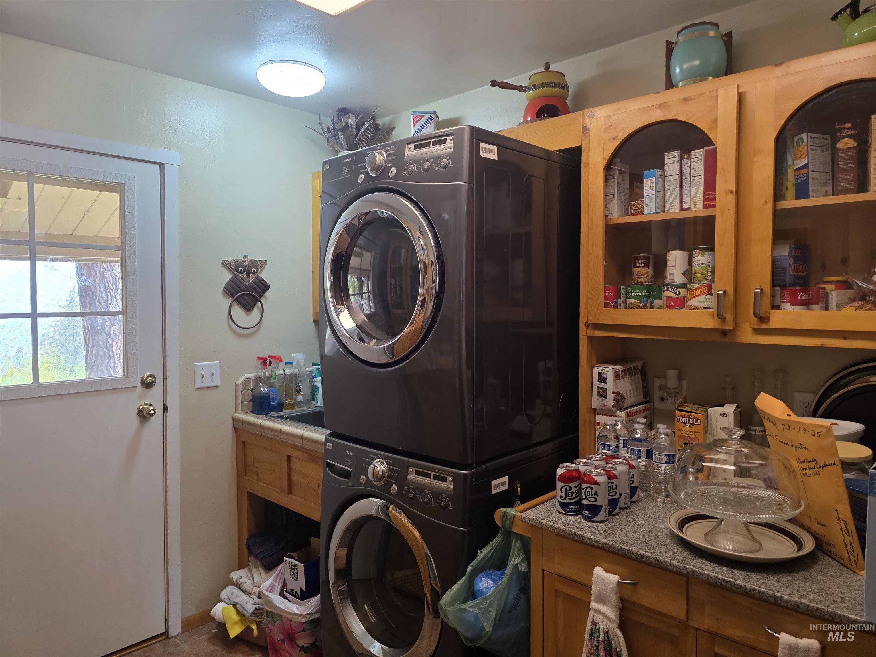 Laundry room featuring stacked washer / drying machine and baseboards