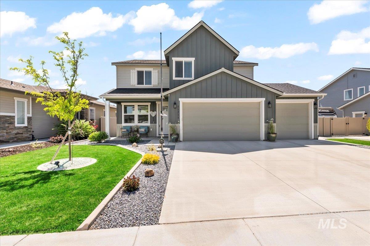 View of front facade featuring board and batten siding, an attached garage, concrete driveway, and covered porch