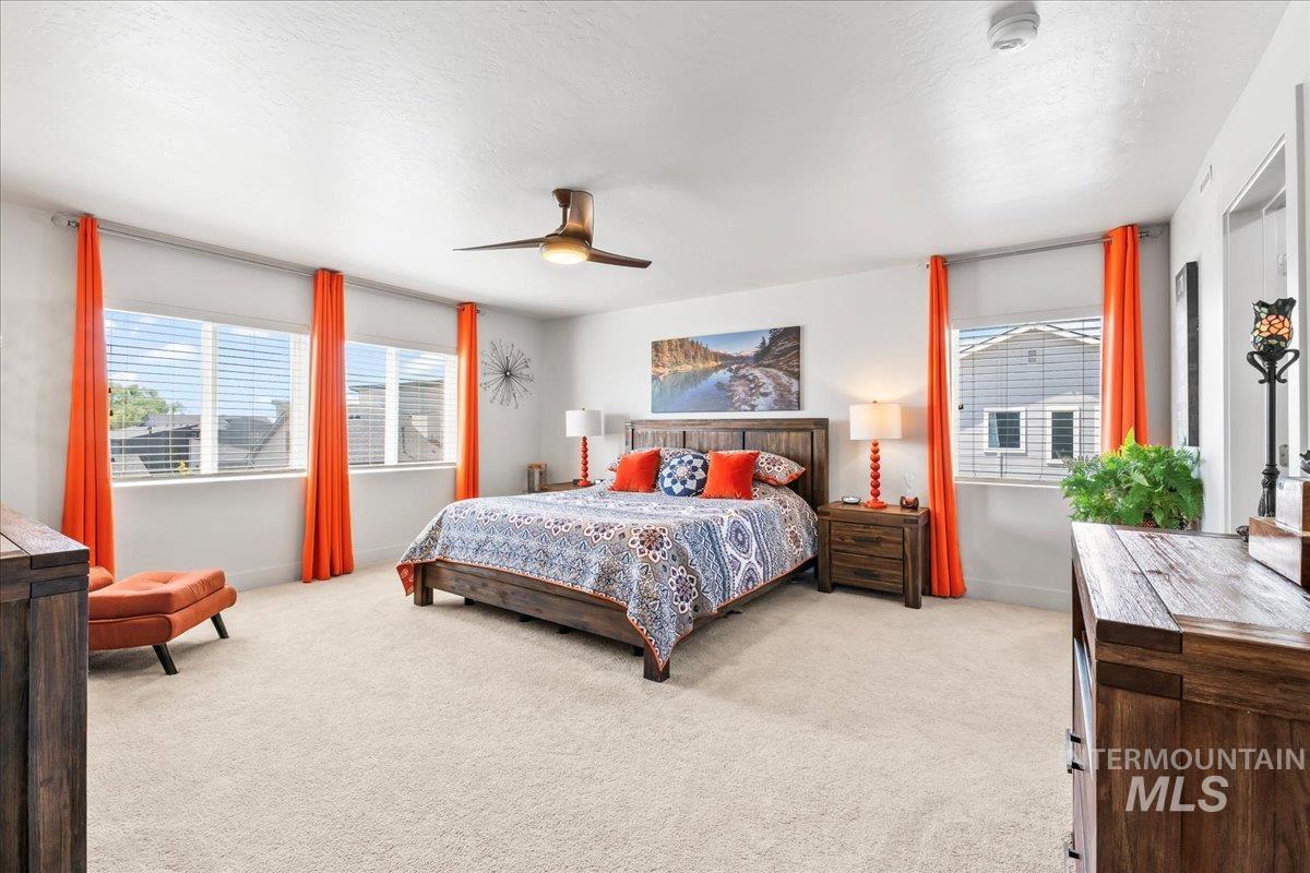Carpeted bedroom with a ceiling fan and a textured ceiling
