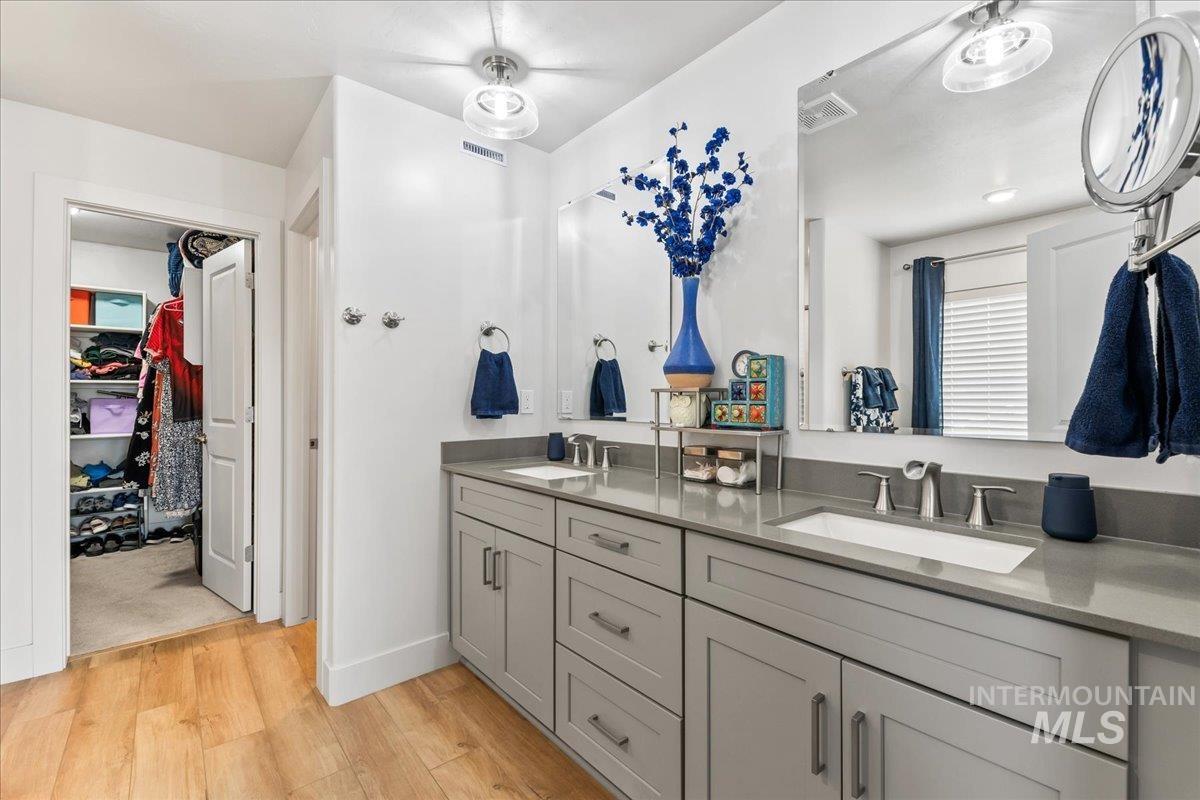 Bathroom featuring a walk in closet, light wood-type flooring, and double vanity