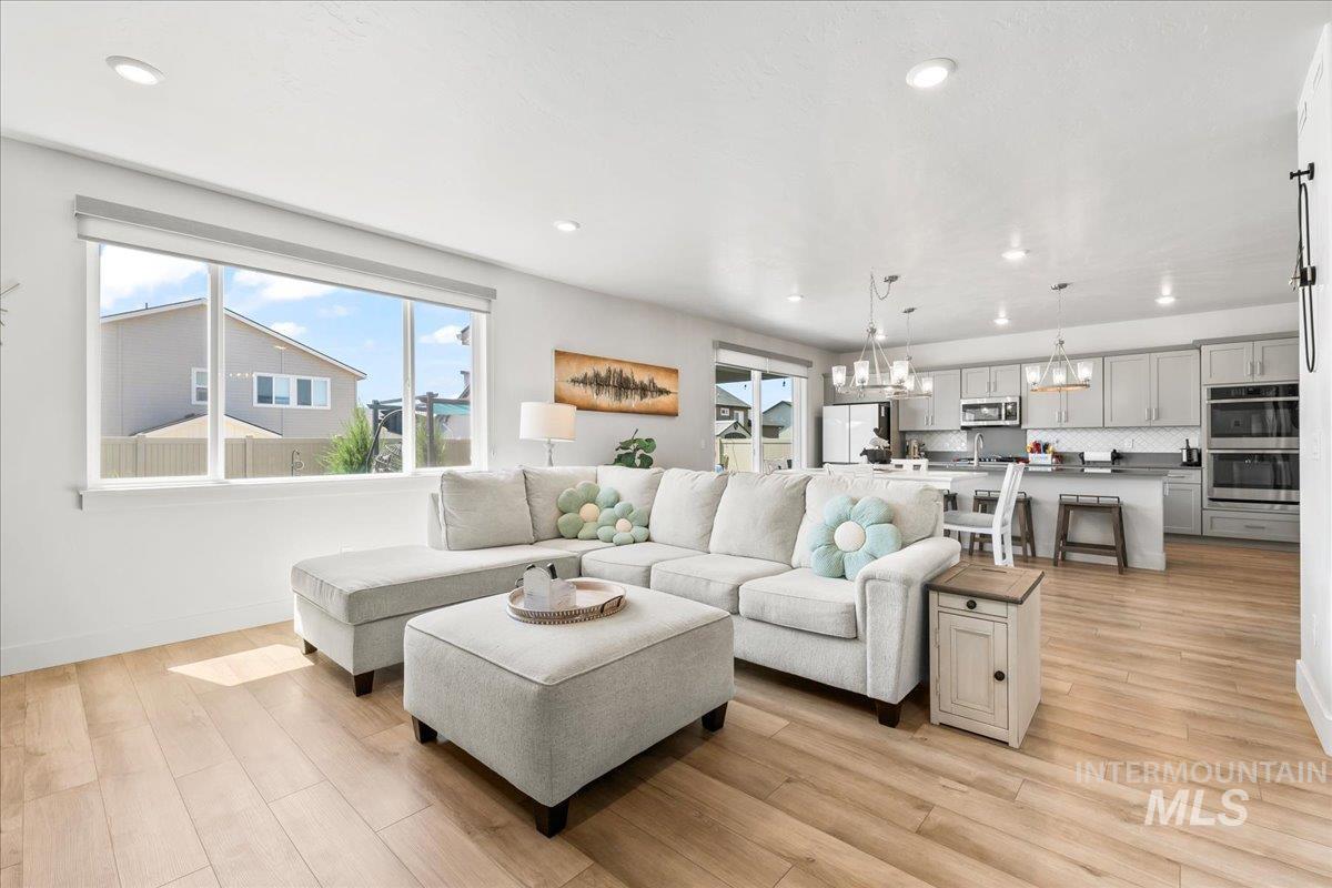 Living area with a chandelier, light wood-style flooring, and recessed lighting