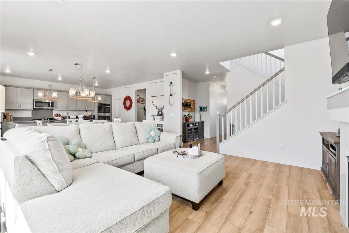 Living room featuring light wood-style flooring, stairway, a chandelier, and recessed lighting