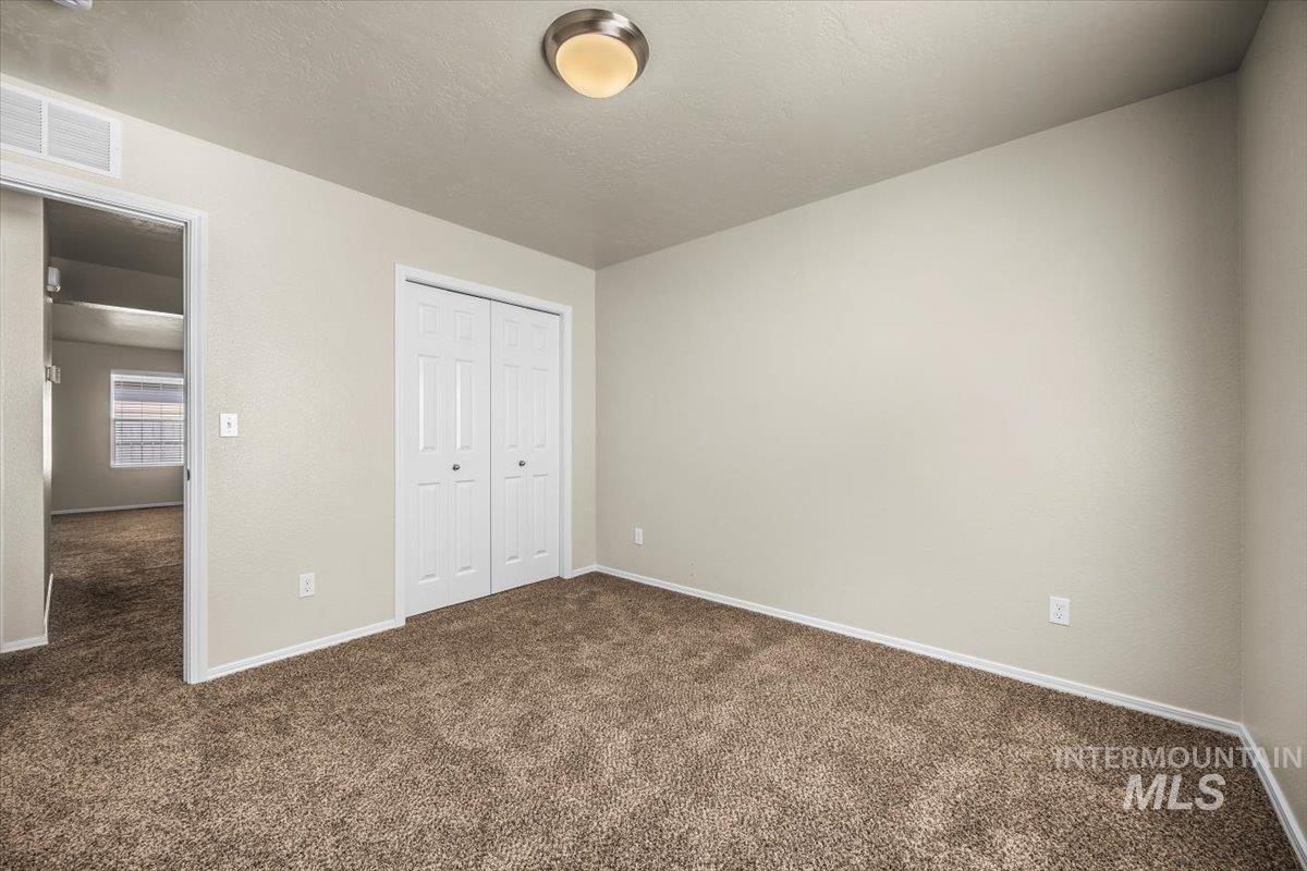 Unfurnished bedroom featuring dark carpet, a closet, and a textured ceiling
