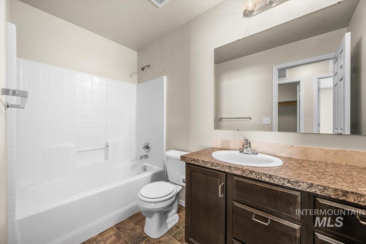 Full bathroom with bathing tub / shower combination, vanity, and a textured wall