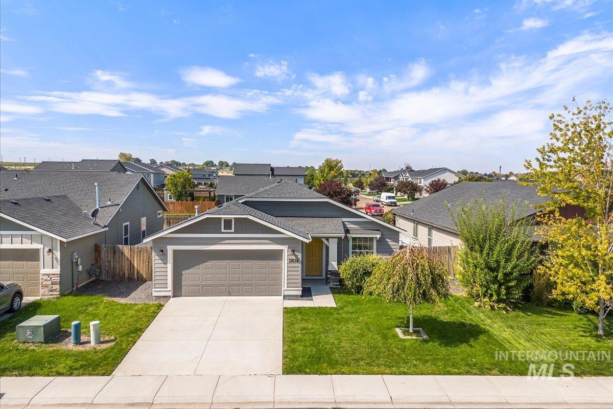 View of front of property with an attached garage, driveway, and a residential view