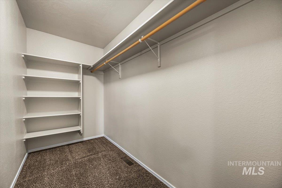 Walk in closet featuring dark colored carpet