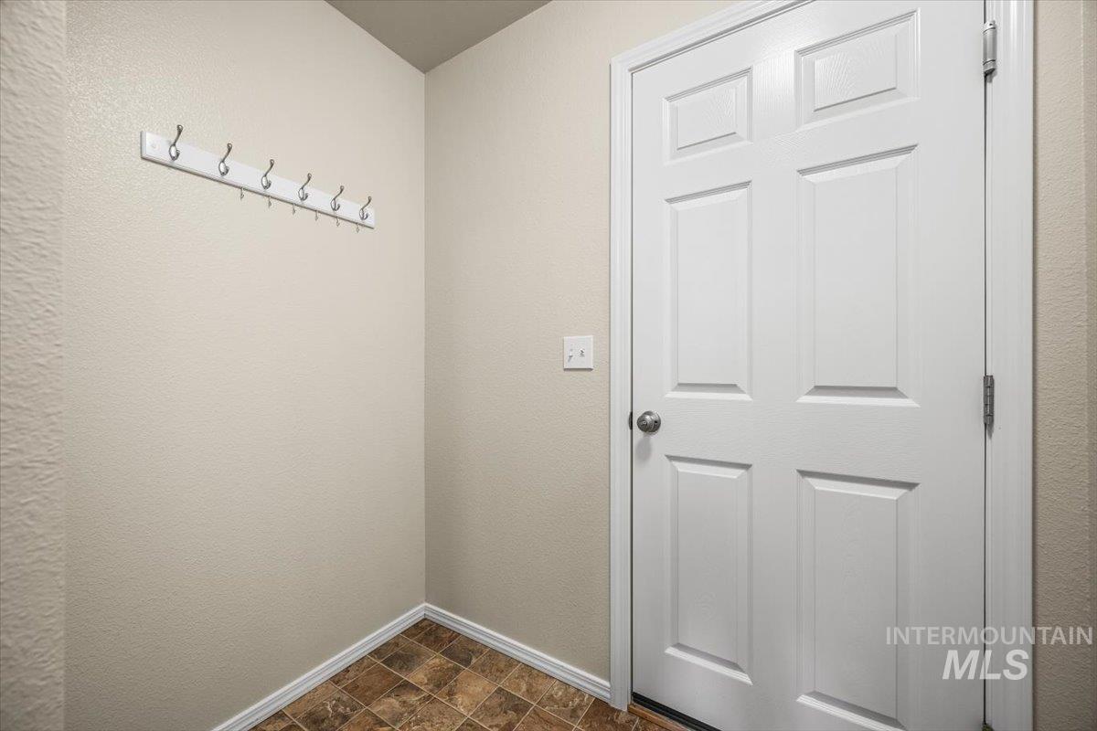 Doorway with stone finish floors and a textured wall