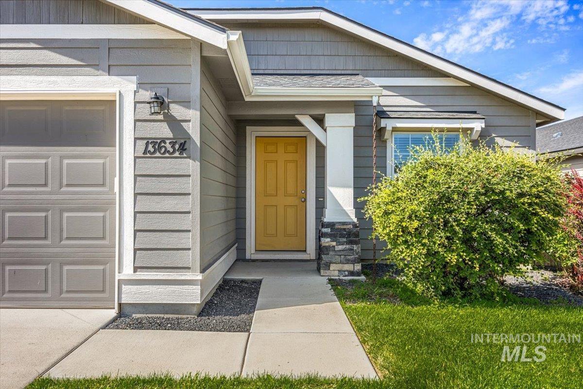 Doorway to property featuring a garage and a lawn