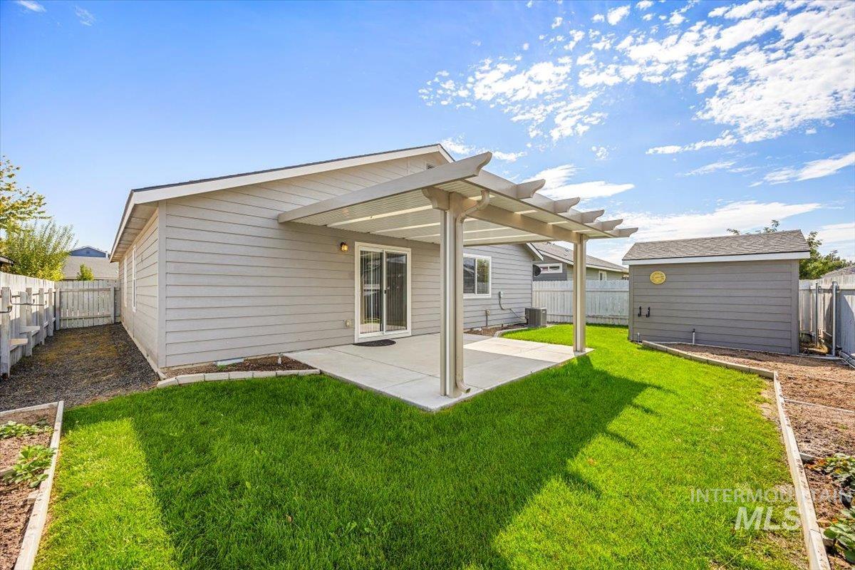Back of house featuring a patio area, a fenced backyard, an outdoor structure, a garden, and a pergola