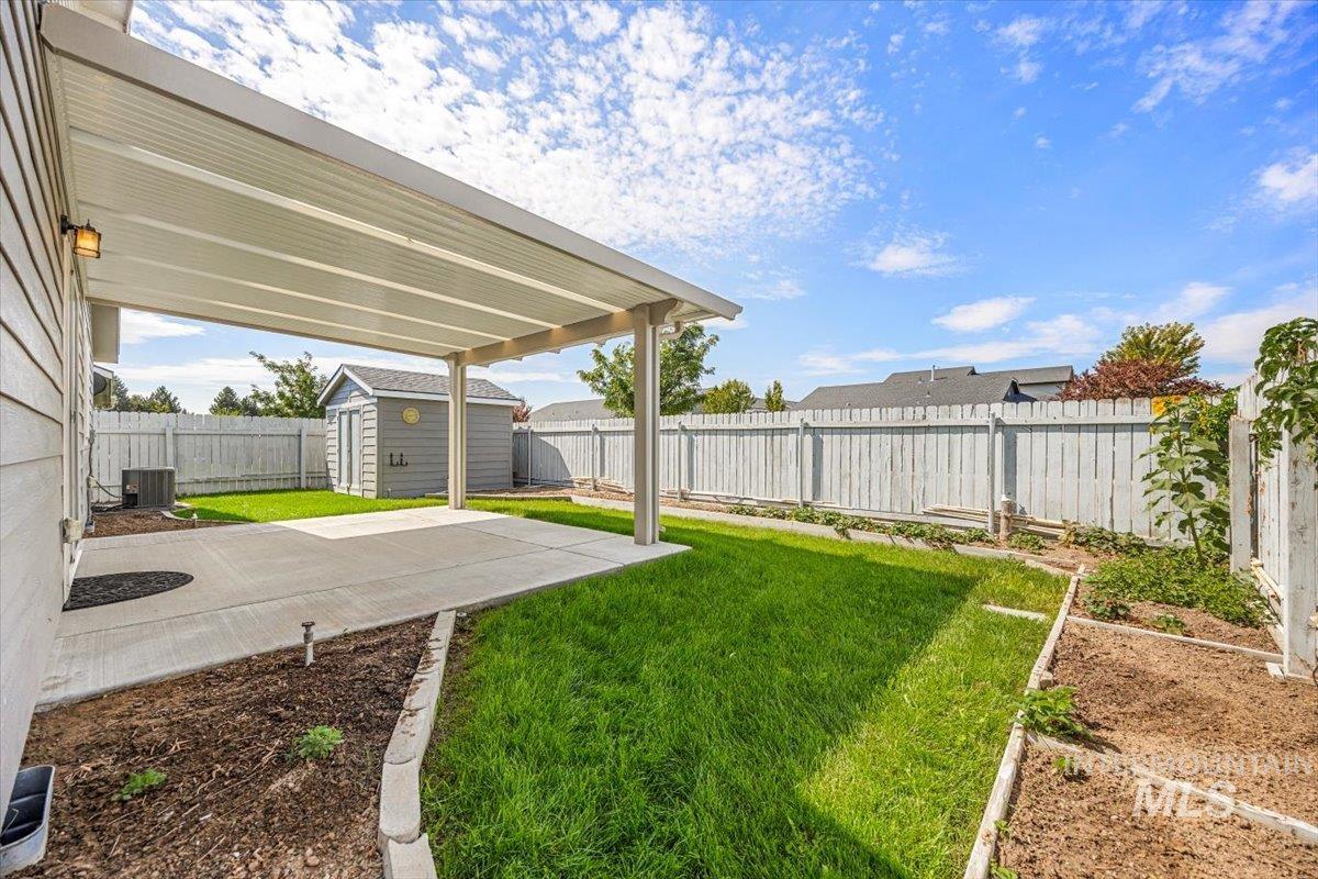 Fenced backyard with a storage unit and a patio