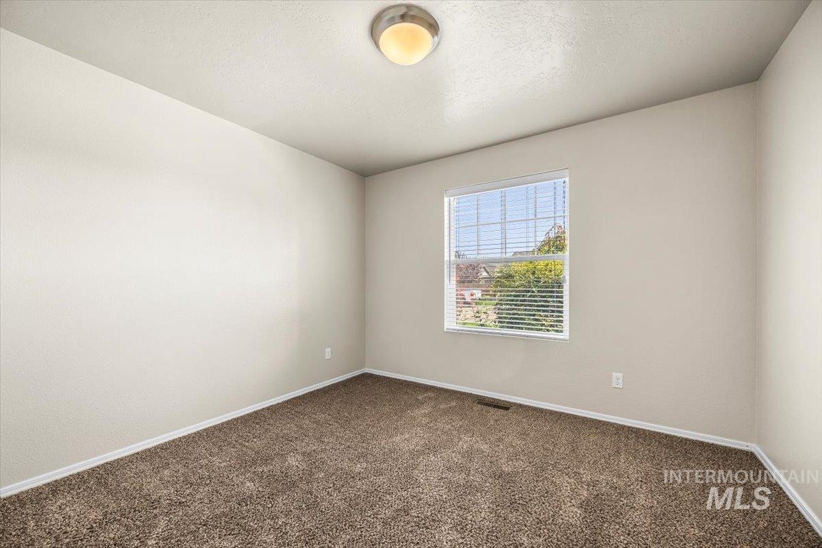 Spare room with dark carpet and a textured ceiling