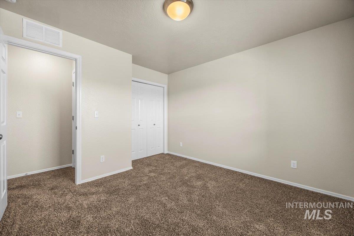 Unfurnished bedroom with dark colored carpet and a closet