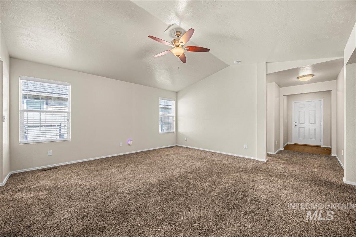 Unfurnished room with dark carpet, lofted ceiling, a textured ceiling, and ceiling fan