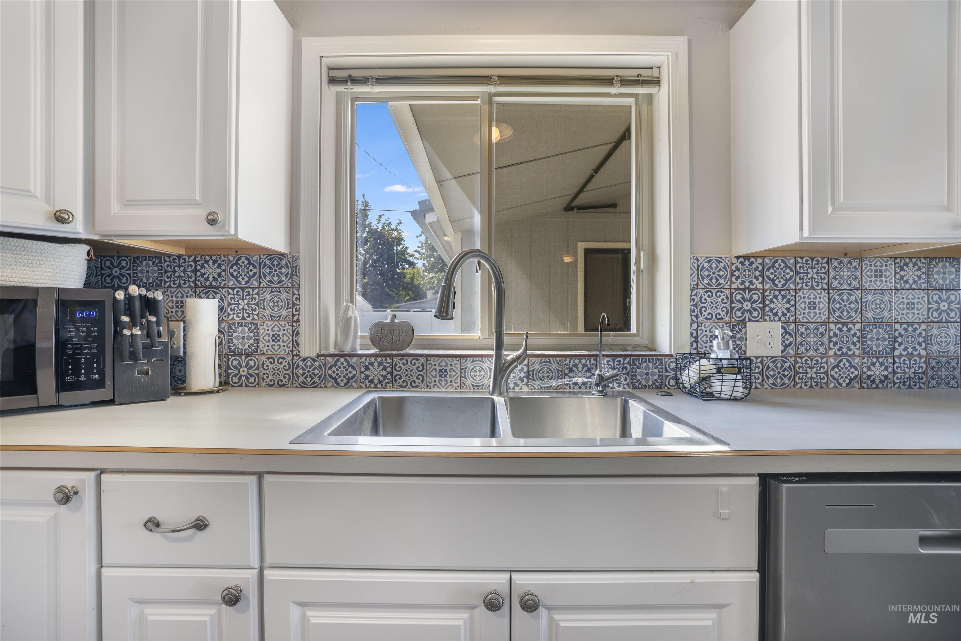 Kitchen featuring white cabinetry, light countertops, and appliances with stainless steel finishes