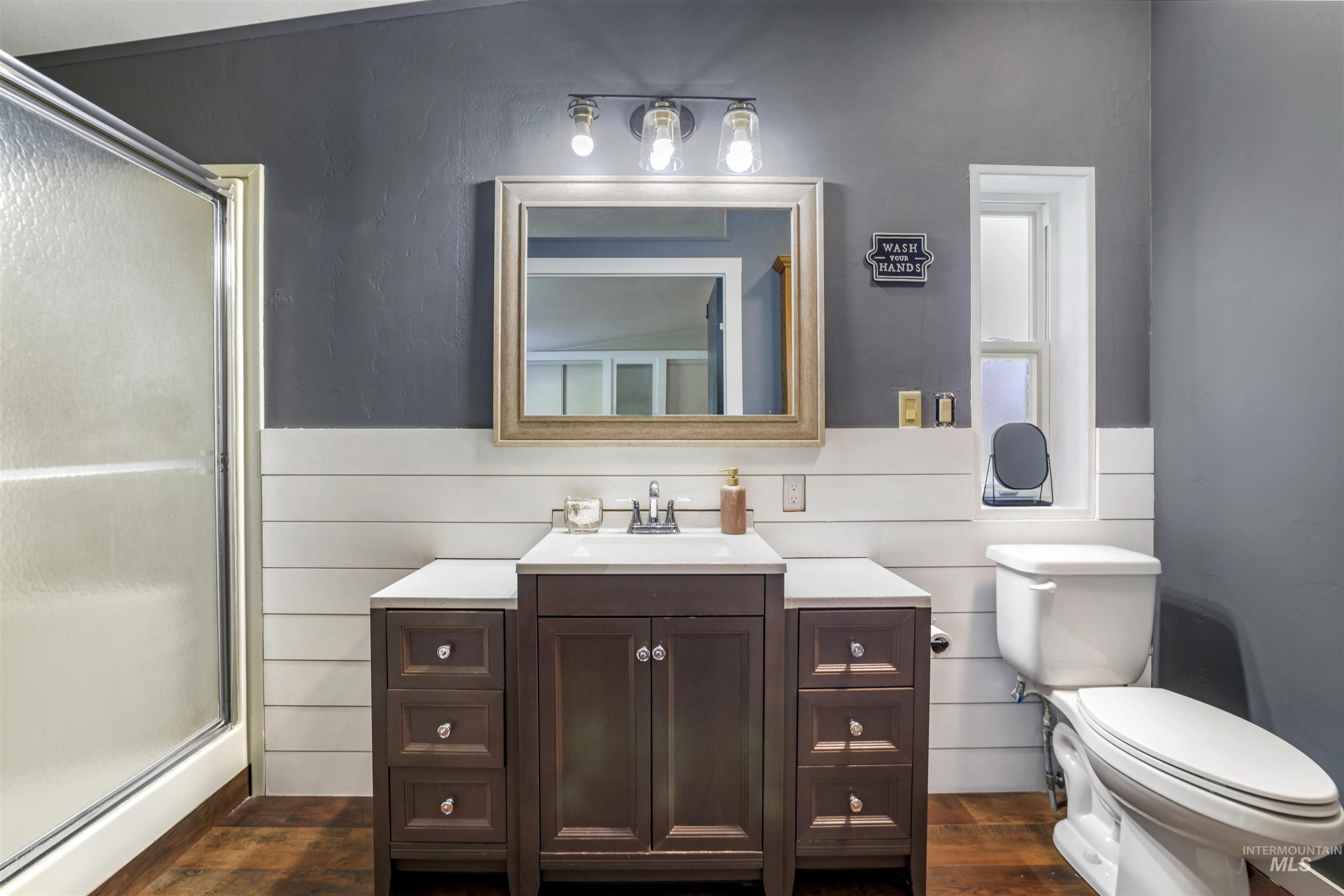 Full bath featuring a stall shower, vanity, and dark wood-type flooring