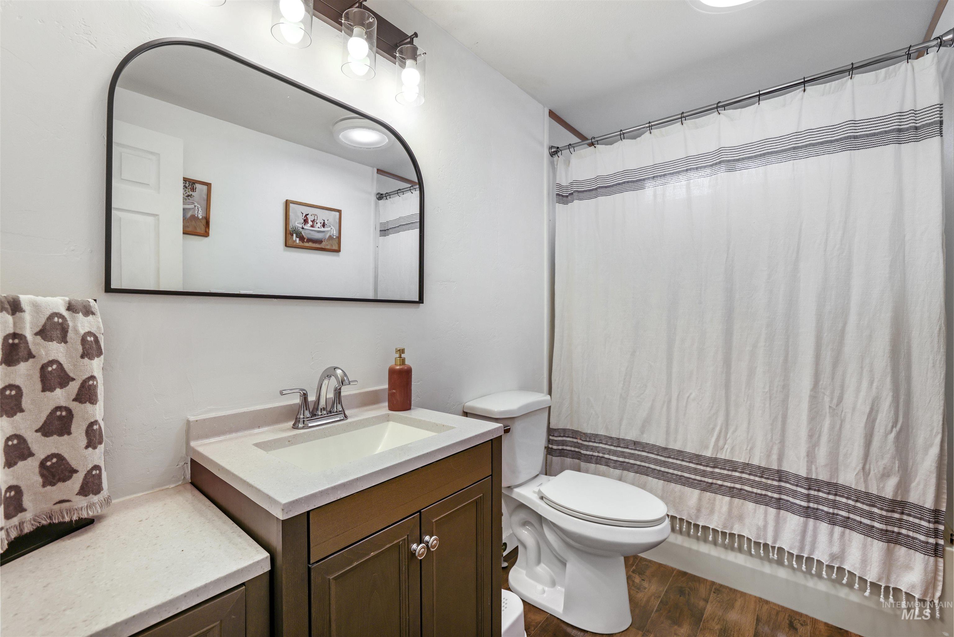 Full bathroom with vanity, dark wood-type flooring, and shower / bath combo