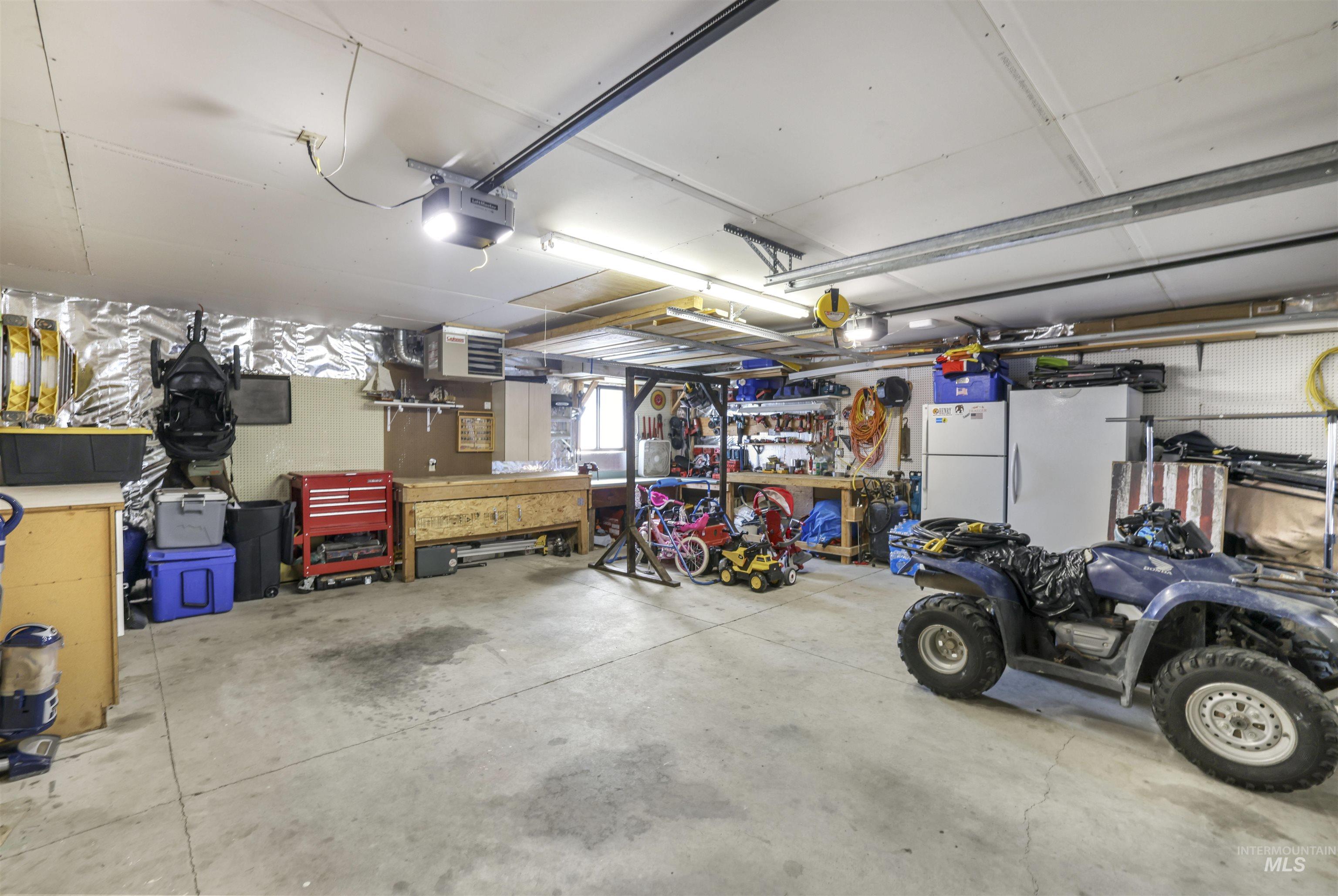 Garage featuring a workshop area, freestanding refrigerator, and a garage door opener