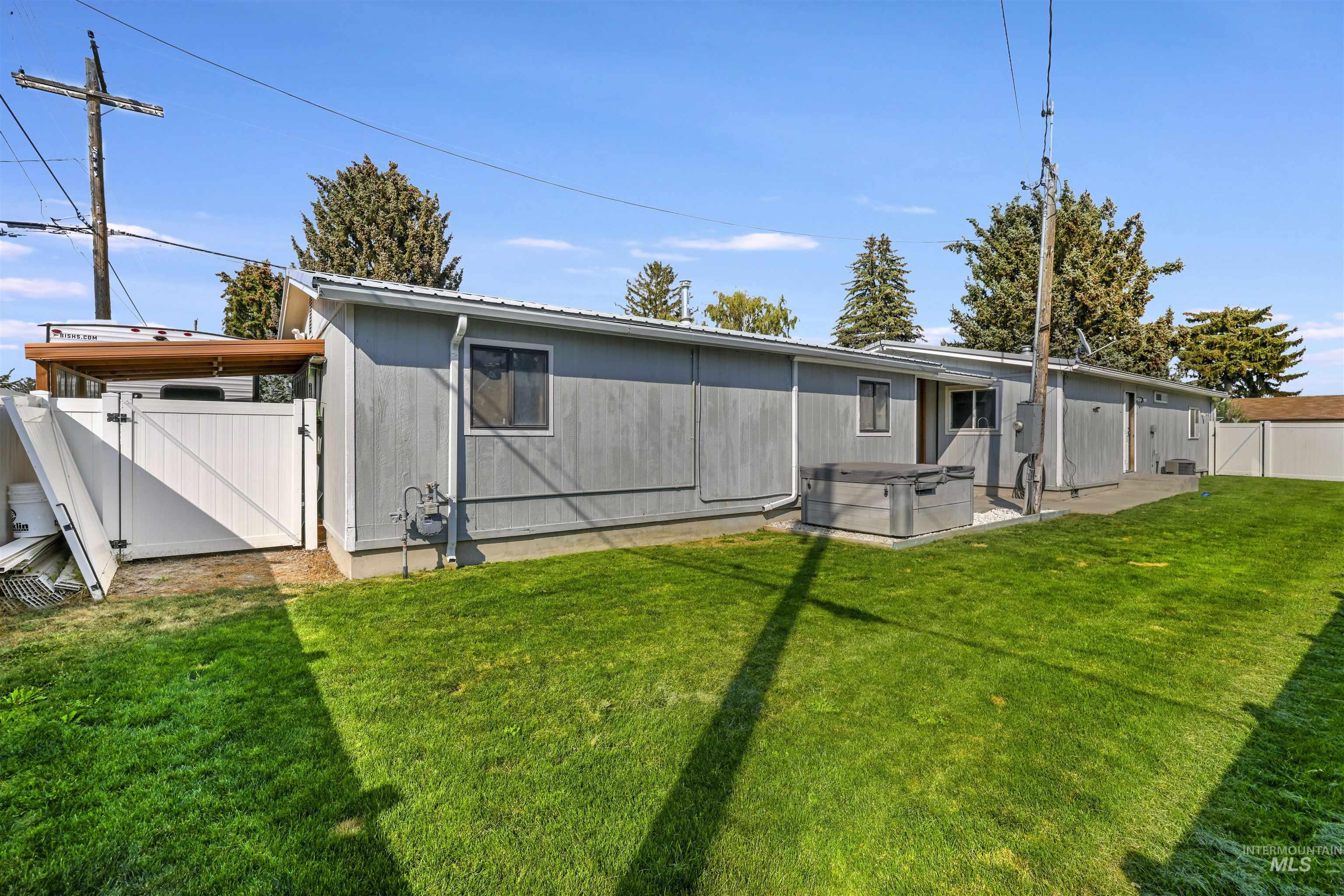 Rear view of property with a gate, a hot tub, a fenced backyard, and a patio
