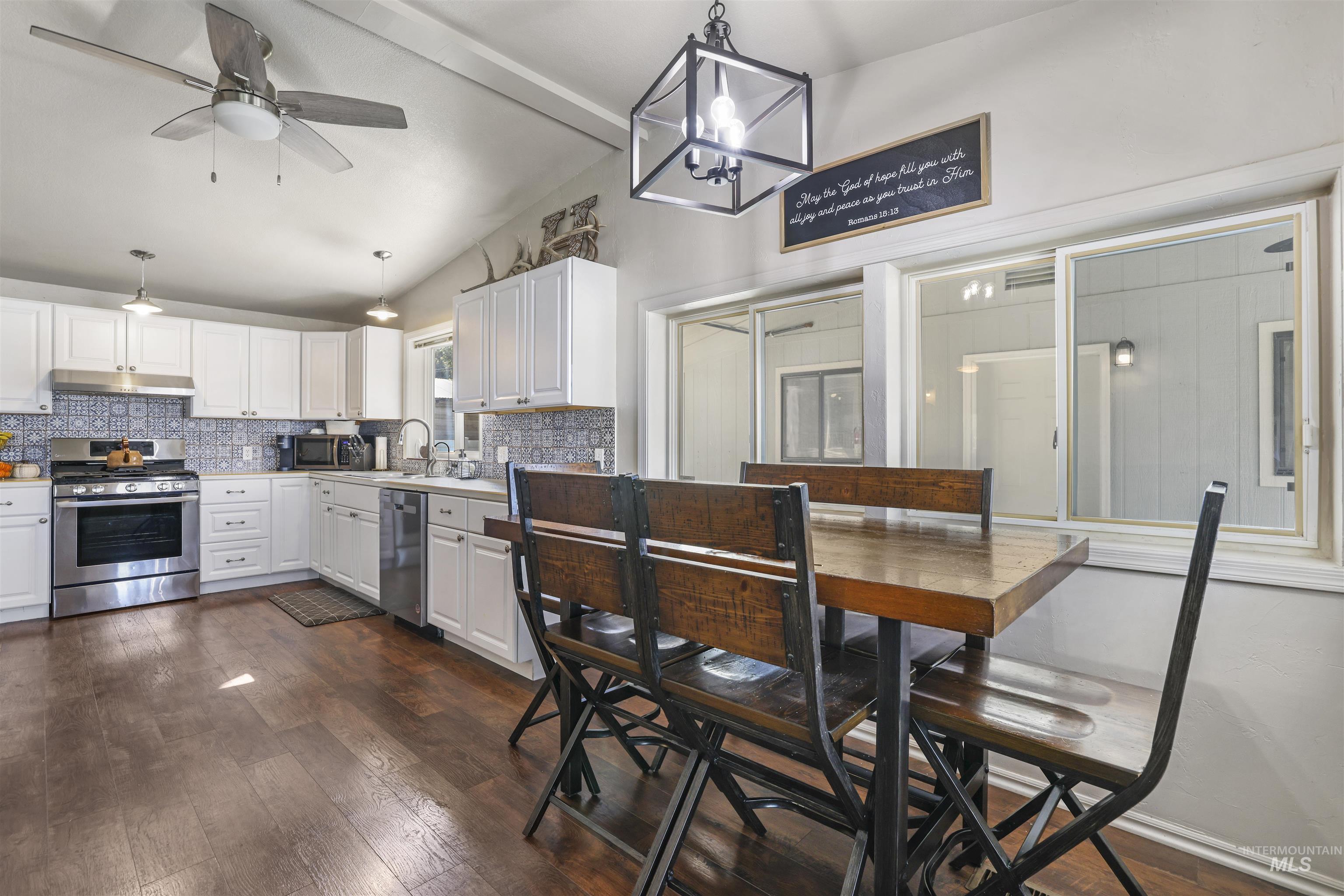 Kitchen featuring hanging light fixtures, white cabinets, stainless steel appliances, and a chandelier