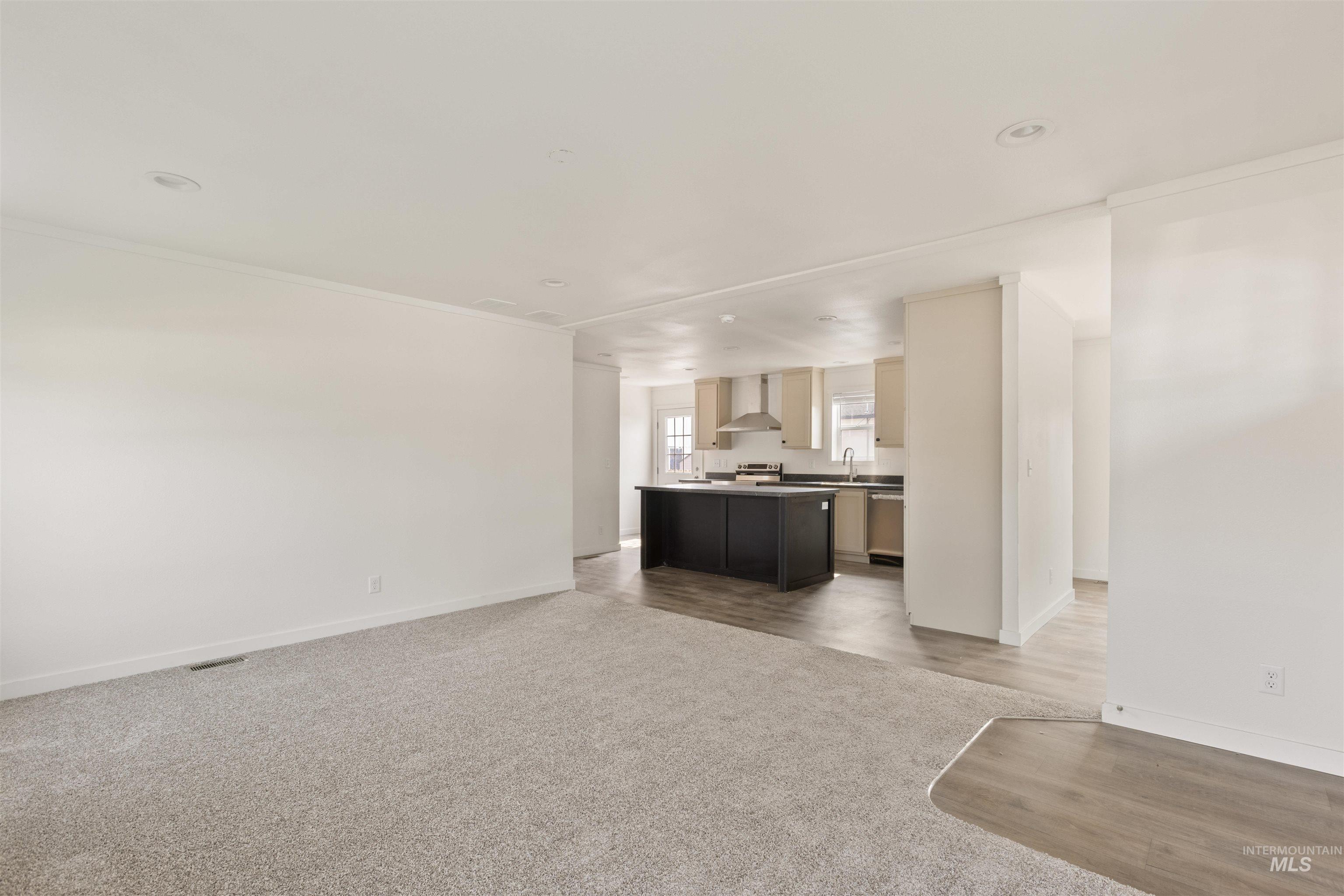 Unfurnished living room with light colored carpet and ornamental molding