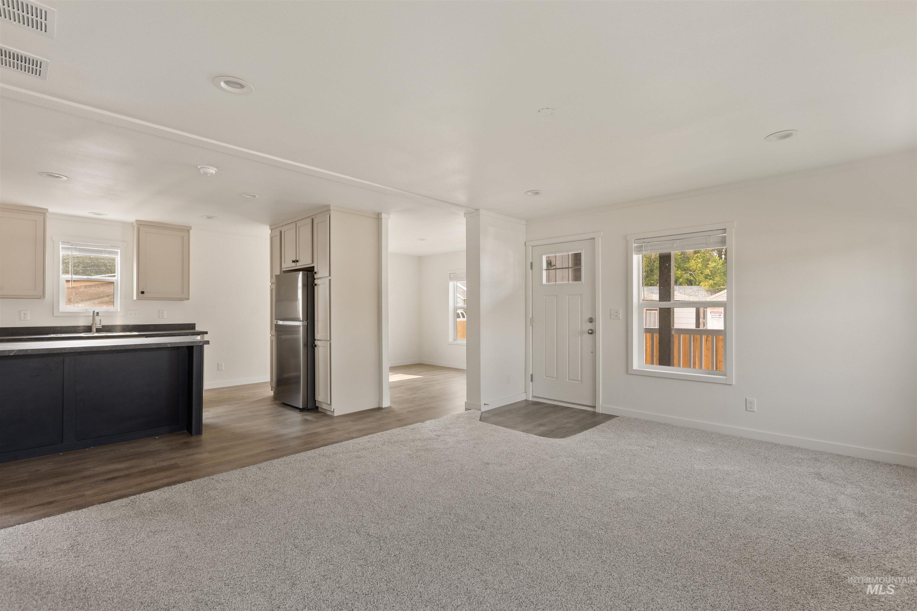 Unfurnished living room featuring dark colored carpet and dark wood-style flooring