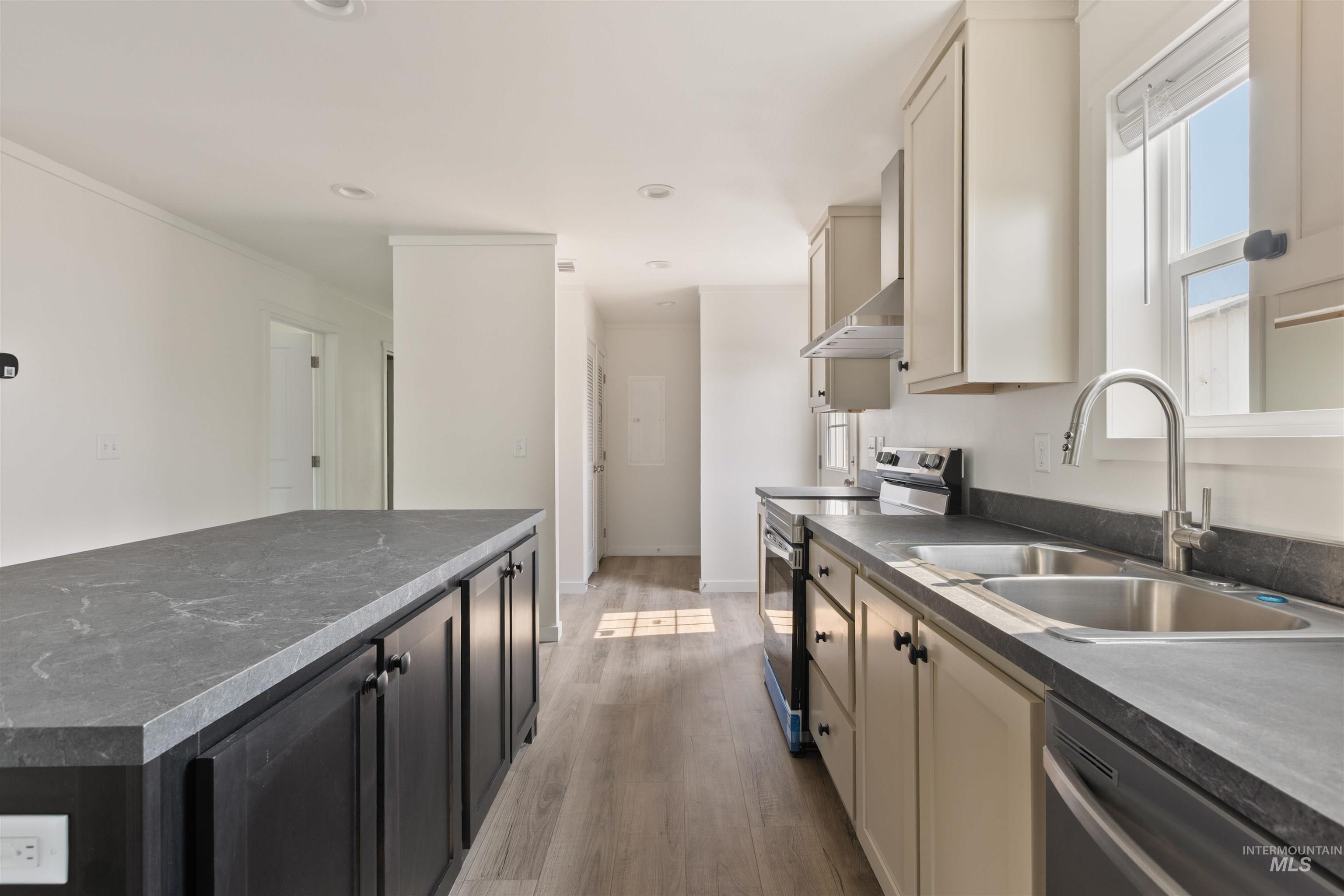 Kitchen featuring dark countertops, appliances with stainless steel finishes, light wood-style floors, dark cabinetry, and recessed lighting