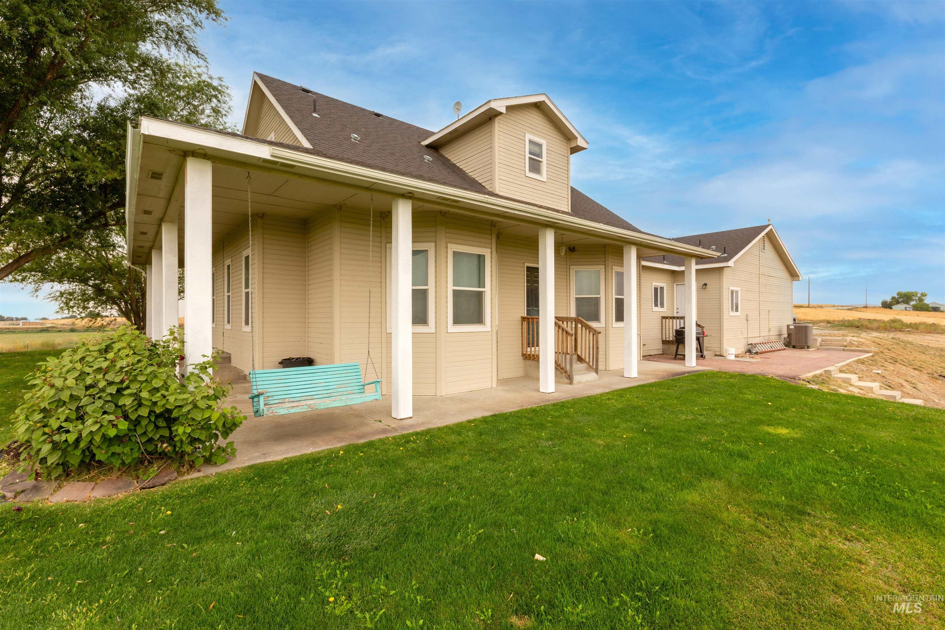 Rear view of property with a lawn, a patio area, and roof with shingles