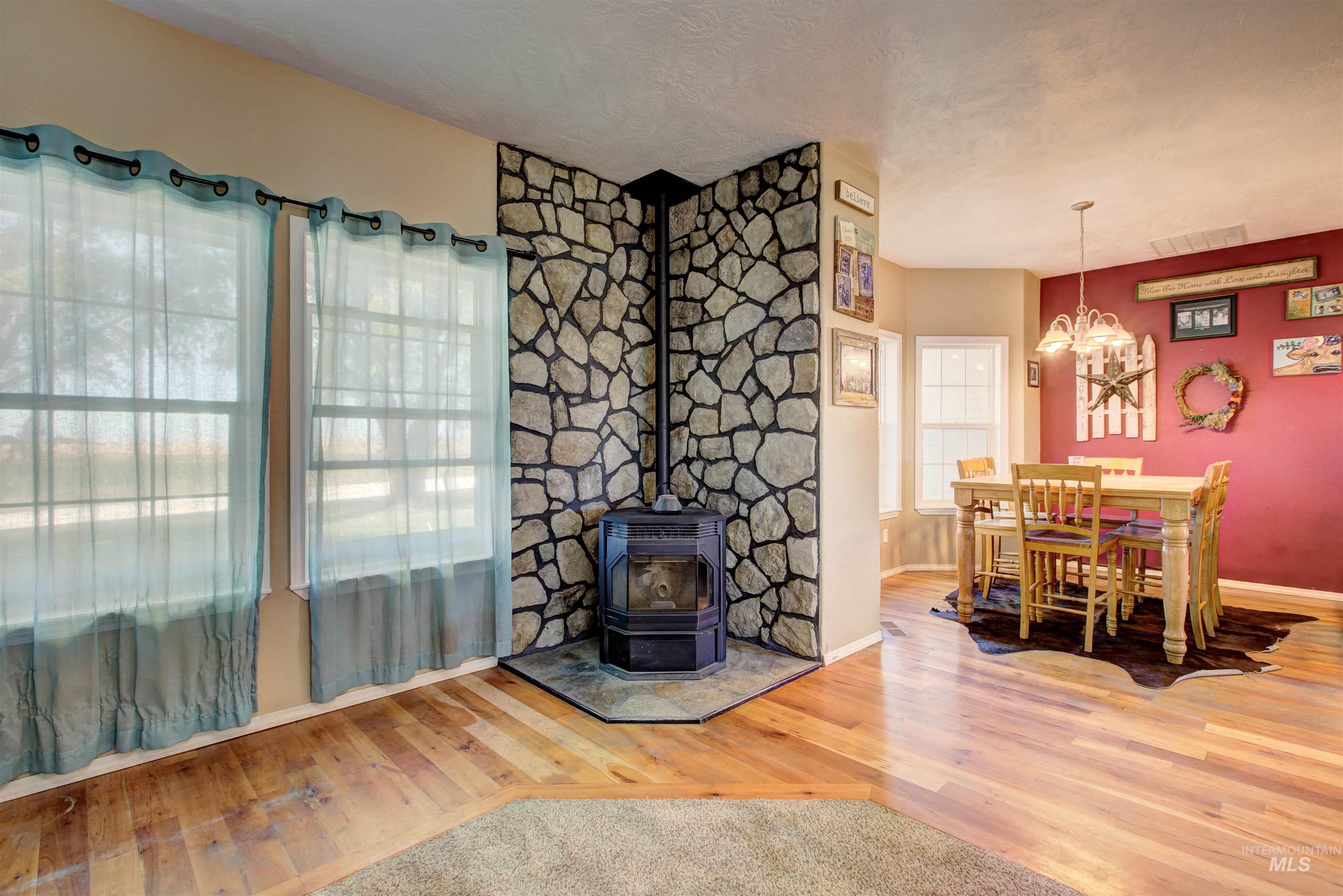 Dining area with a wood stove, wood finished floors, a textured ceiling, and a chandelier