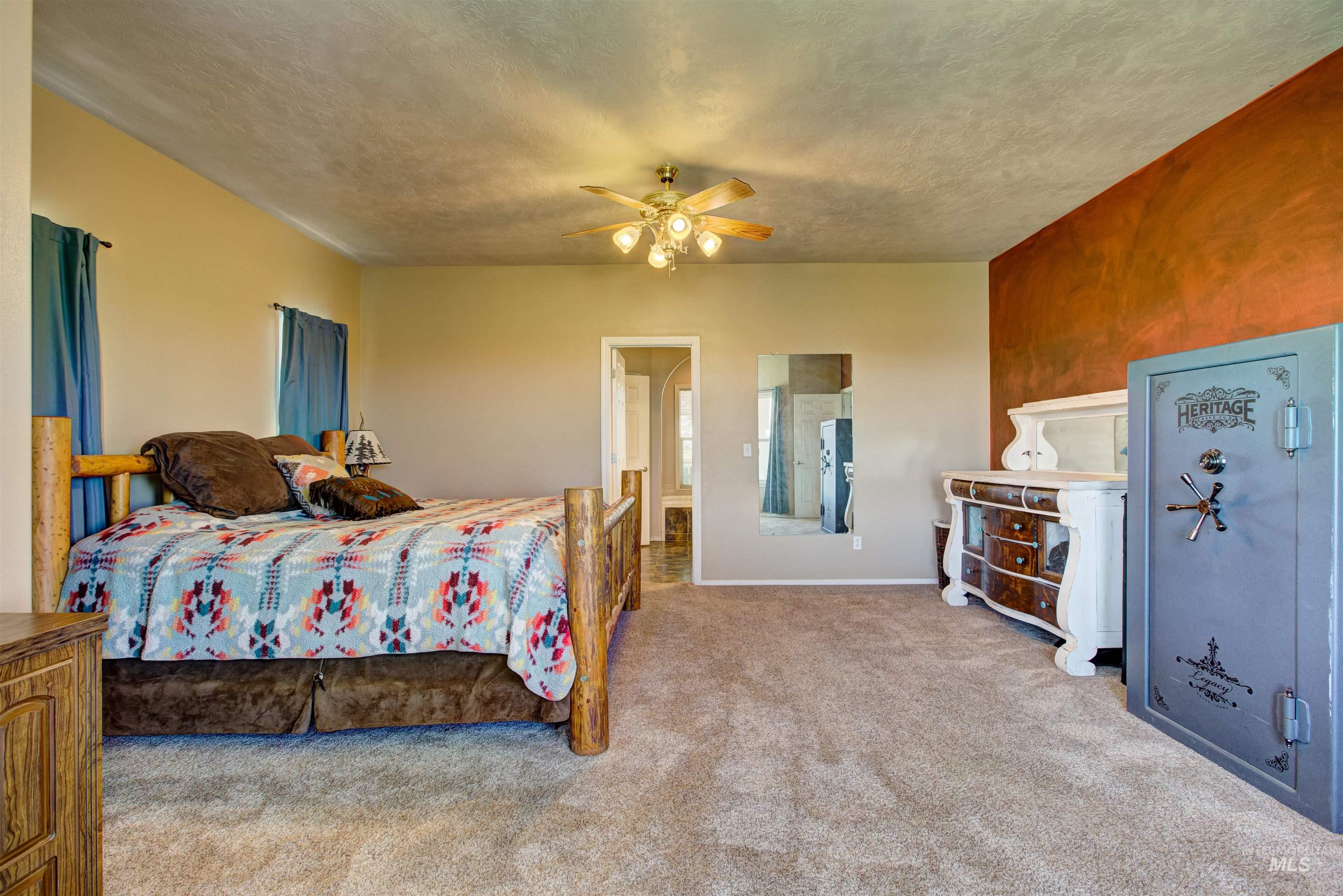 Bedroom featuring light colored carpet, ceiling fan, a textured ceiling, and ensuite bath