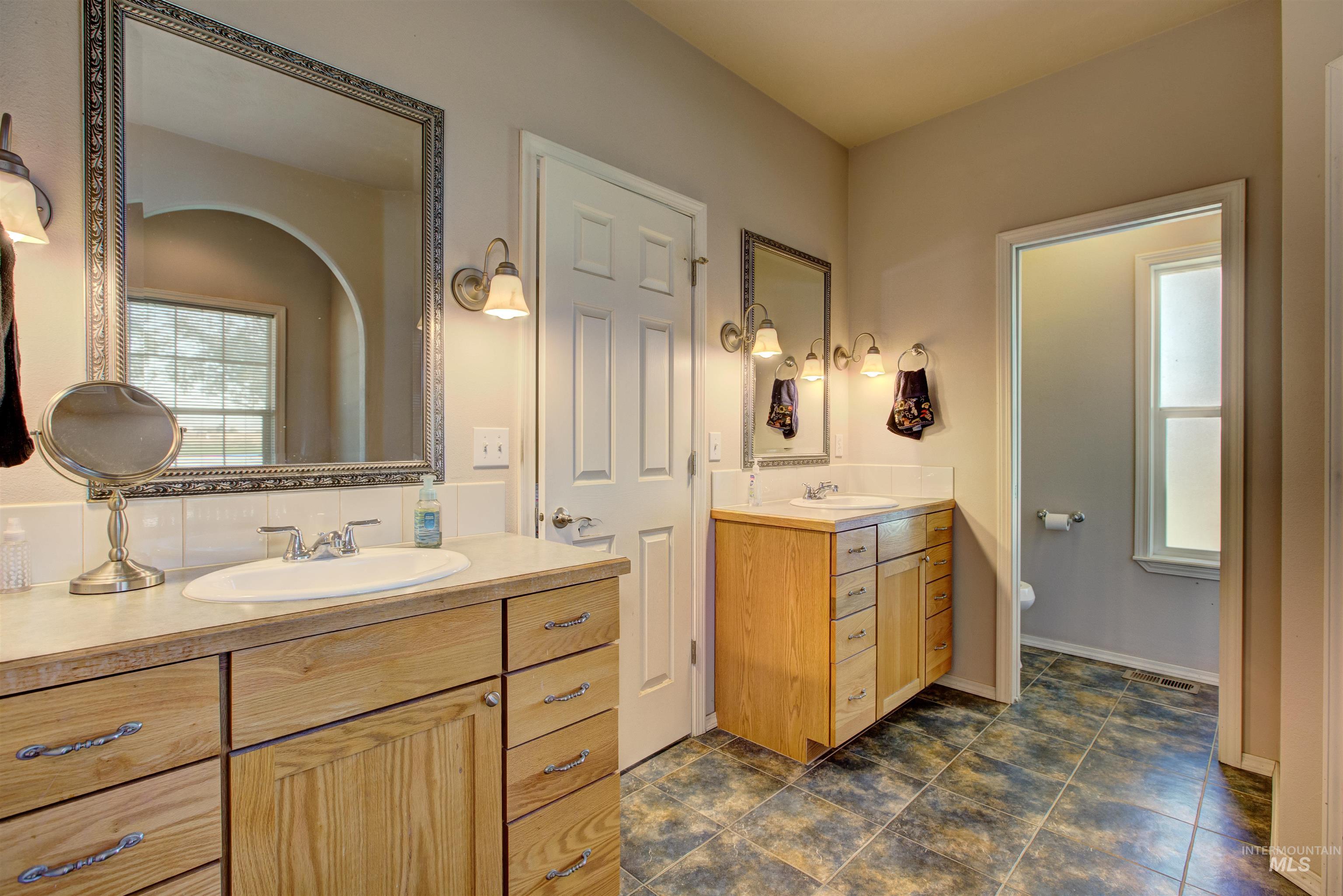 Full bath with two vanities and dark tile patterned floors