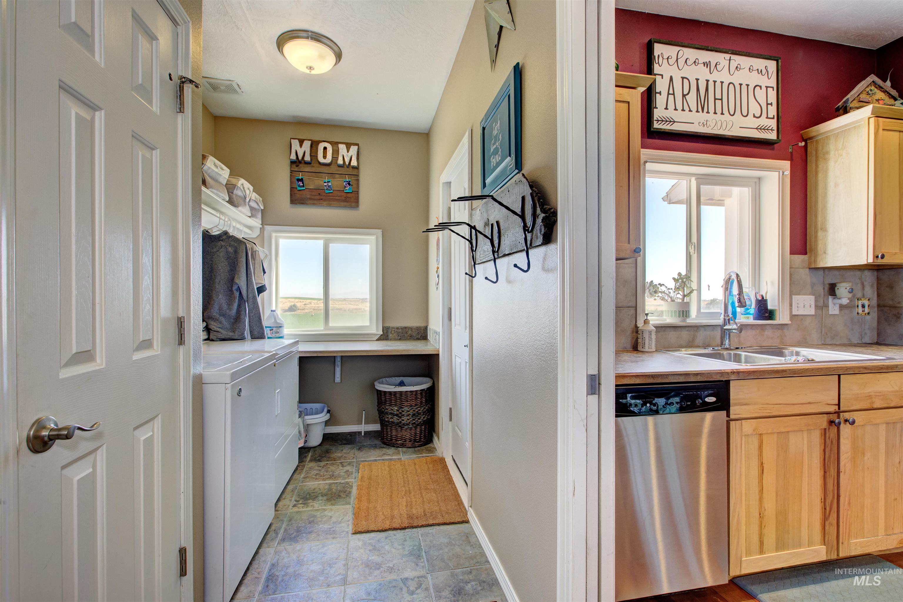 Laundry room featuring healthy amount of natural light, washer and dryer, and stone finish flooring
