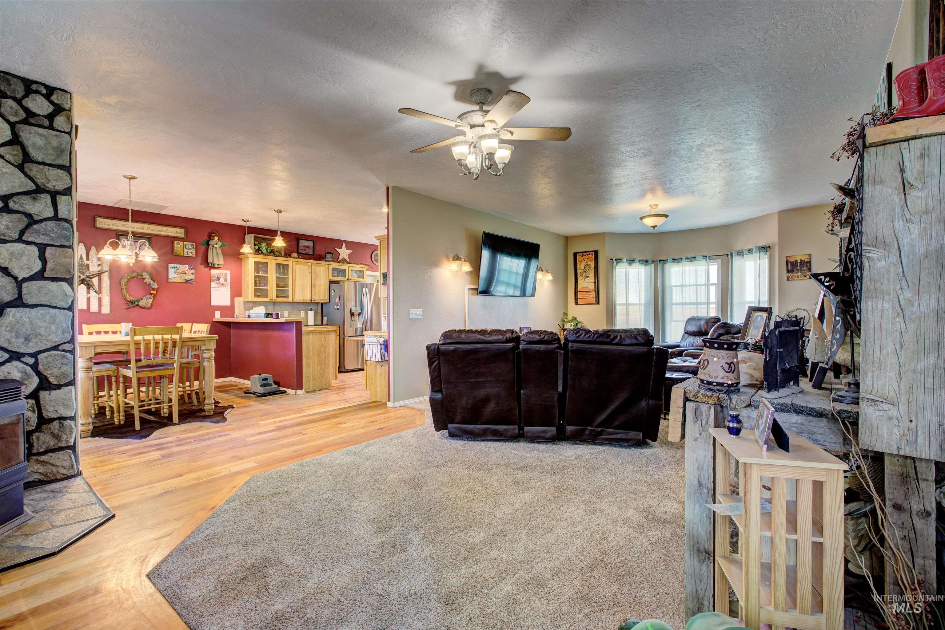 Living area featuring a textured ceiling, light wood finished floors, a ceiling fan, and a chandelier