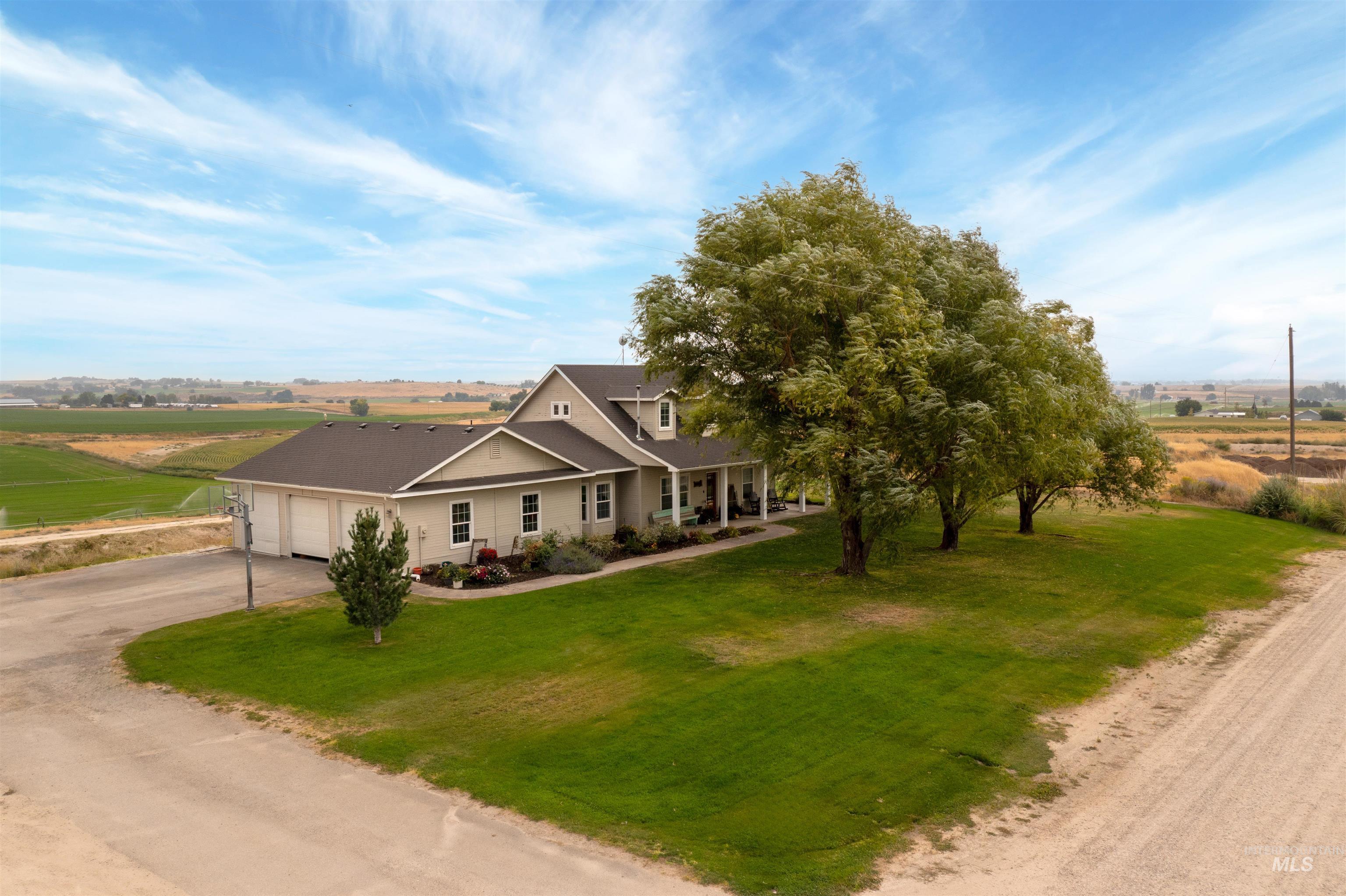 View of front of property with covered porch, driveway, a view of countryside, and a front lawn