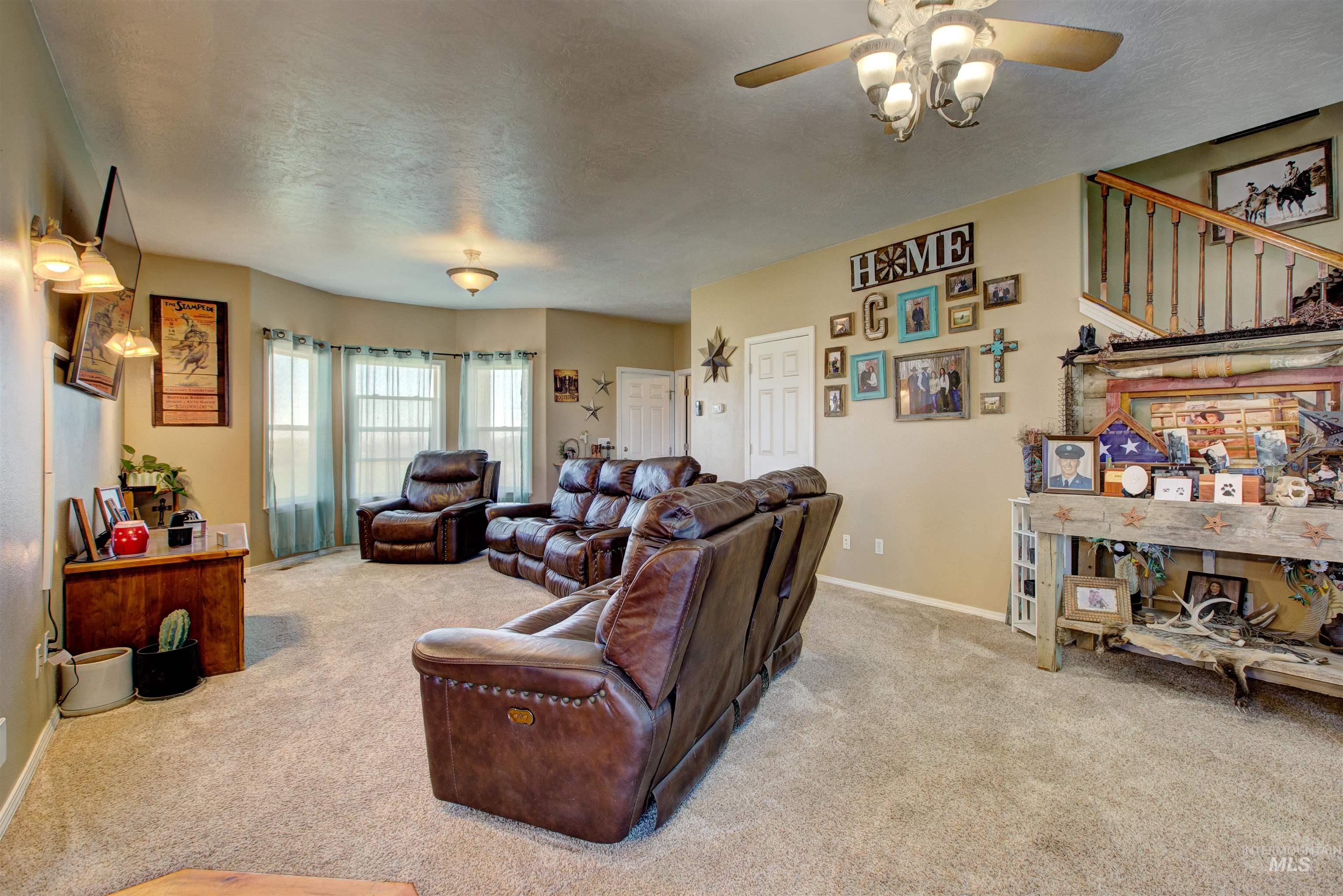 Living room featuring light carpet, a ceiling fan, and a textured ceiling