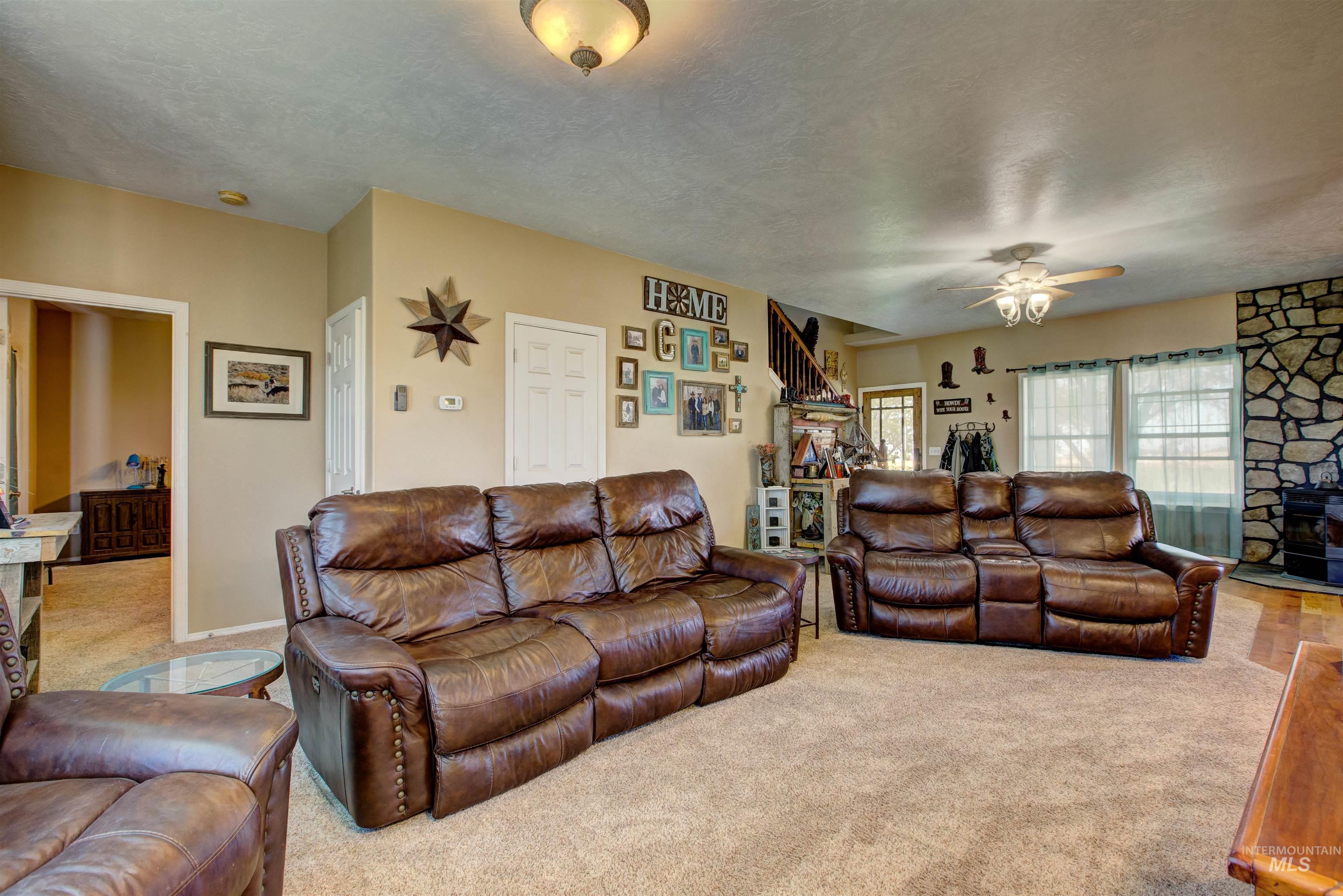 Living area with carpet, a ceiling fan, a textured ceiling, a fireplace, and stairway