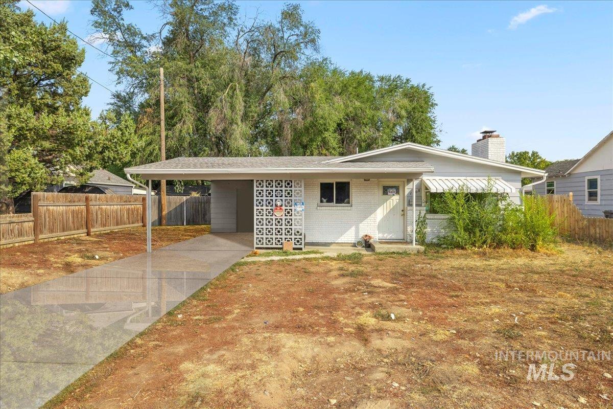View of front of property with a carport, concrete driveway, brick siding, and a chimney
