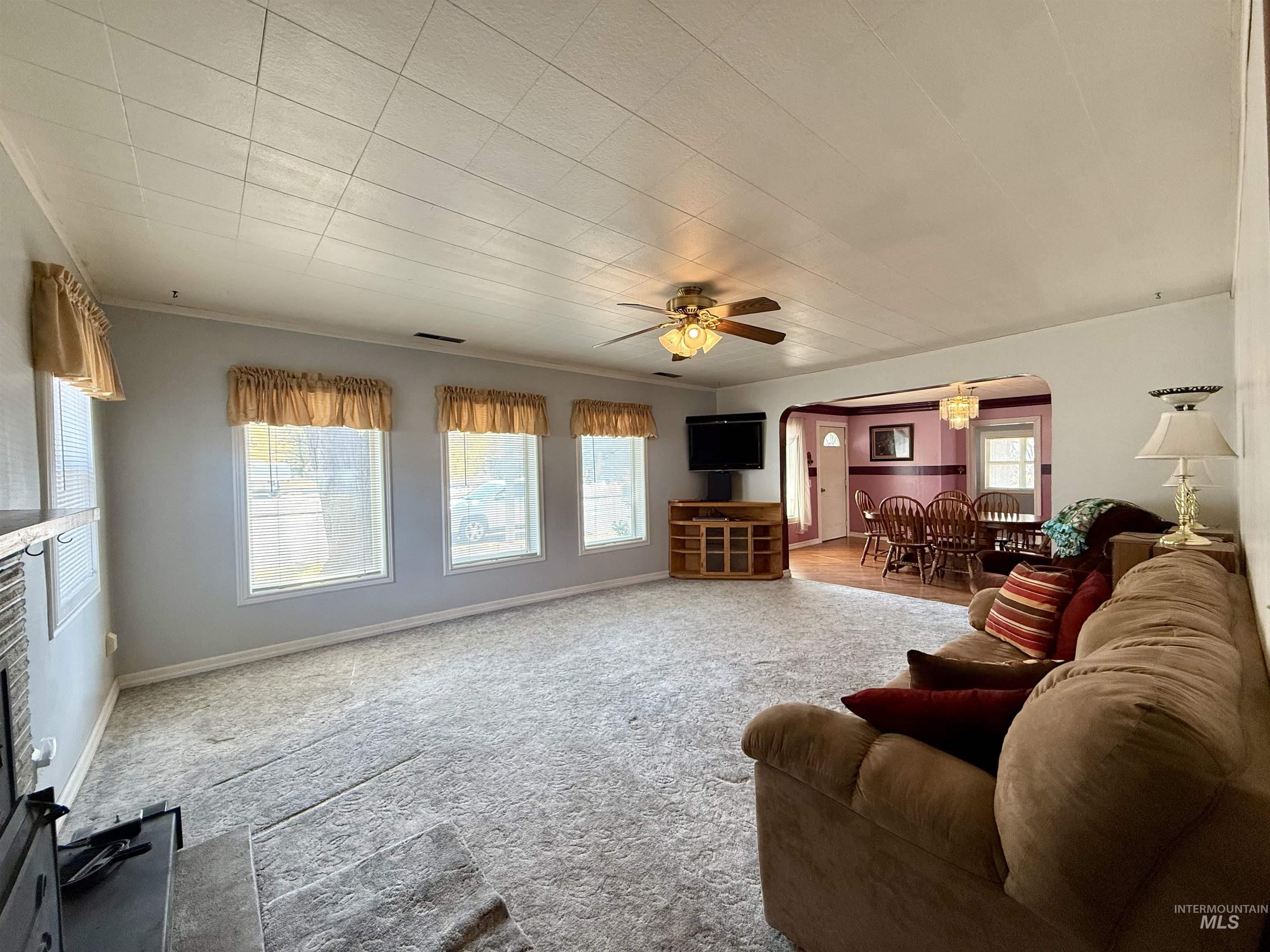 Carpeted living area featuring arched walkways and ceiling fan