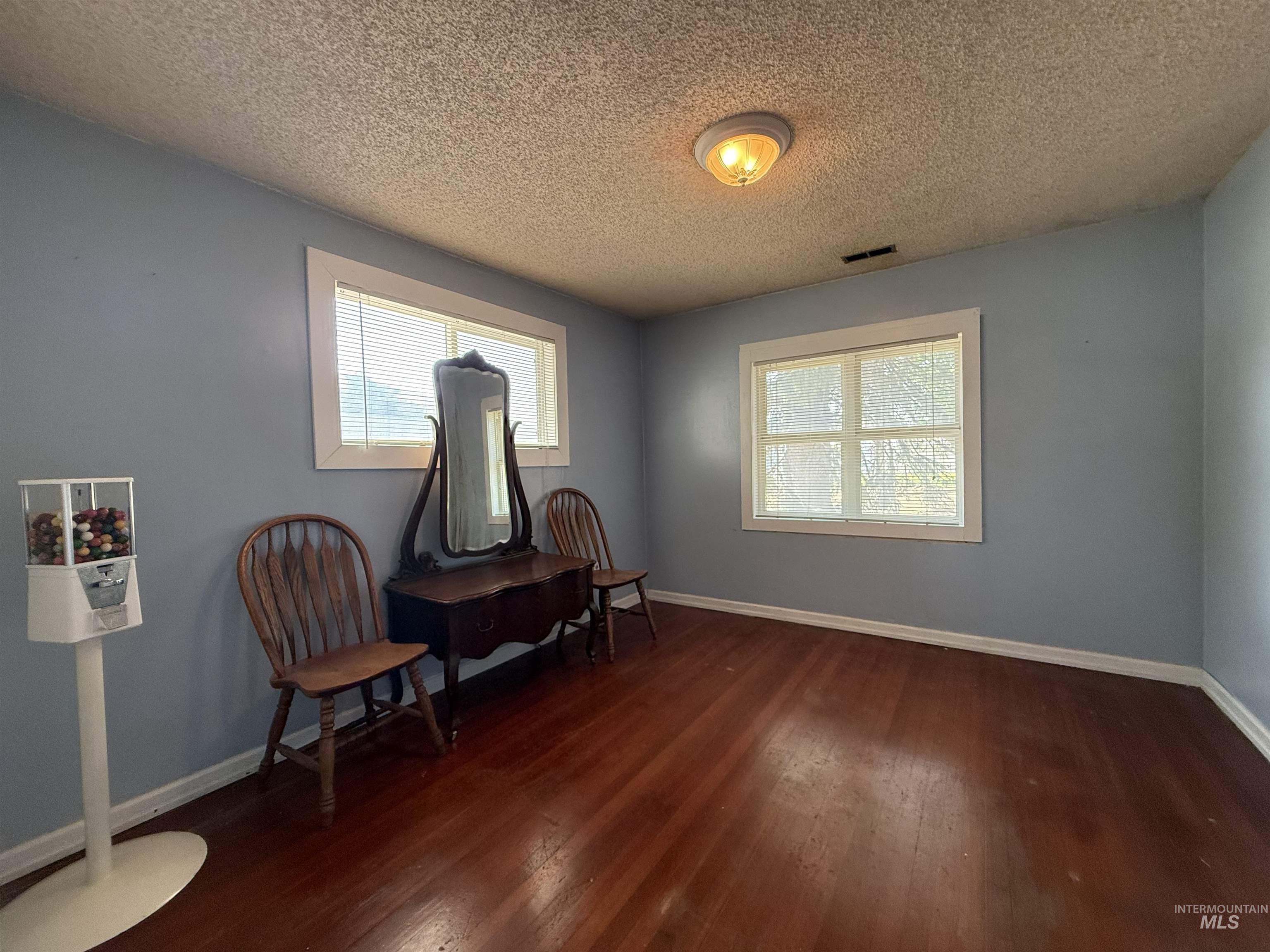 Living area with dark wood-type flooring, healthy amount of natural light, and a textured ceiling