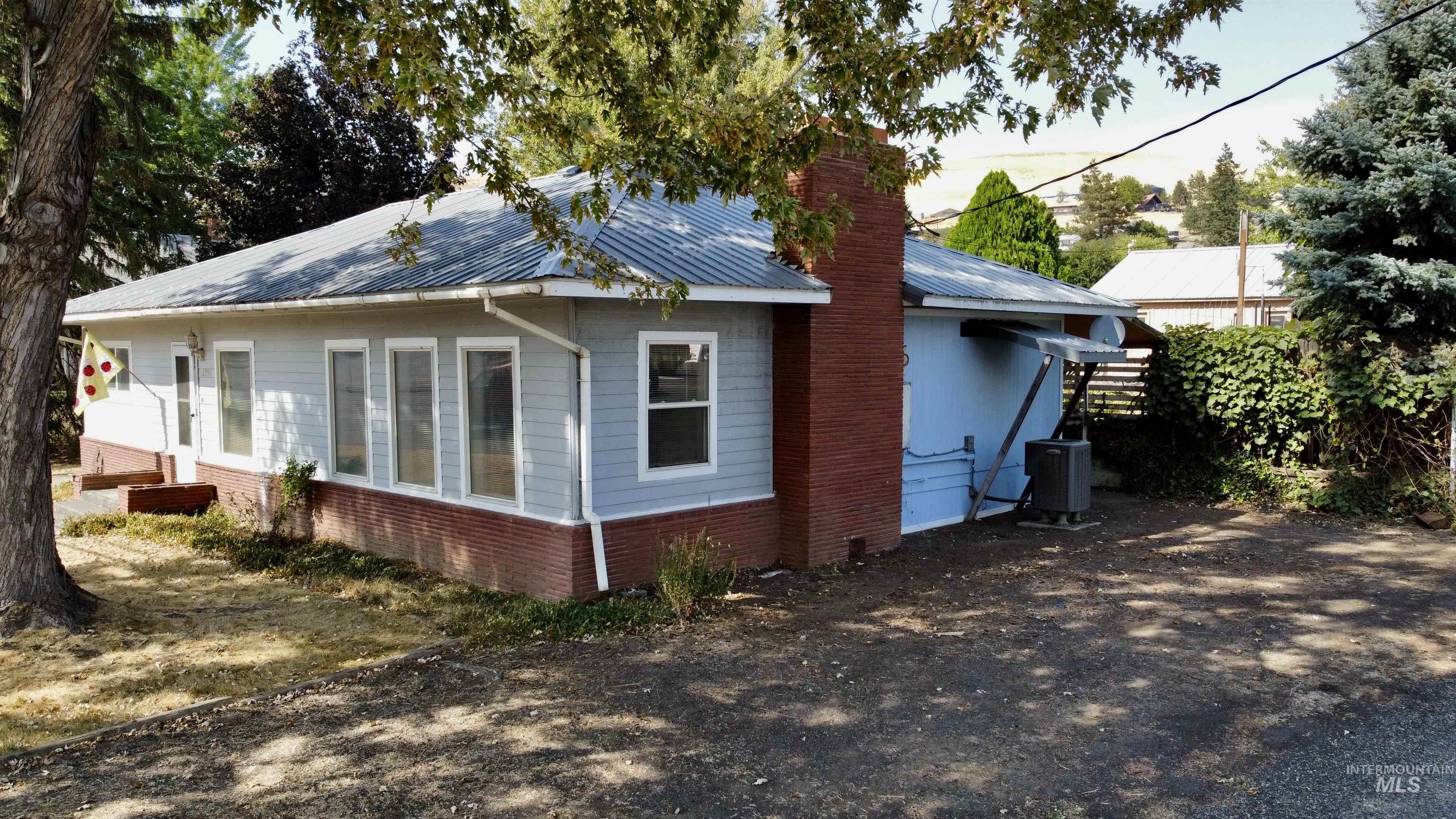 View of side of property featuring a metal roof, a chimney, and brick siding