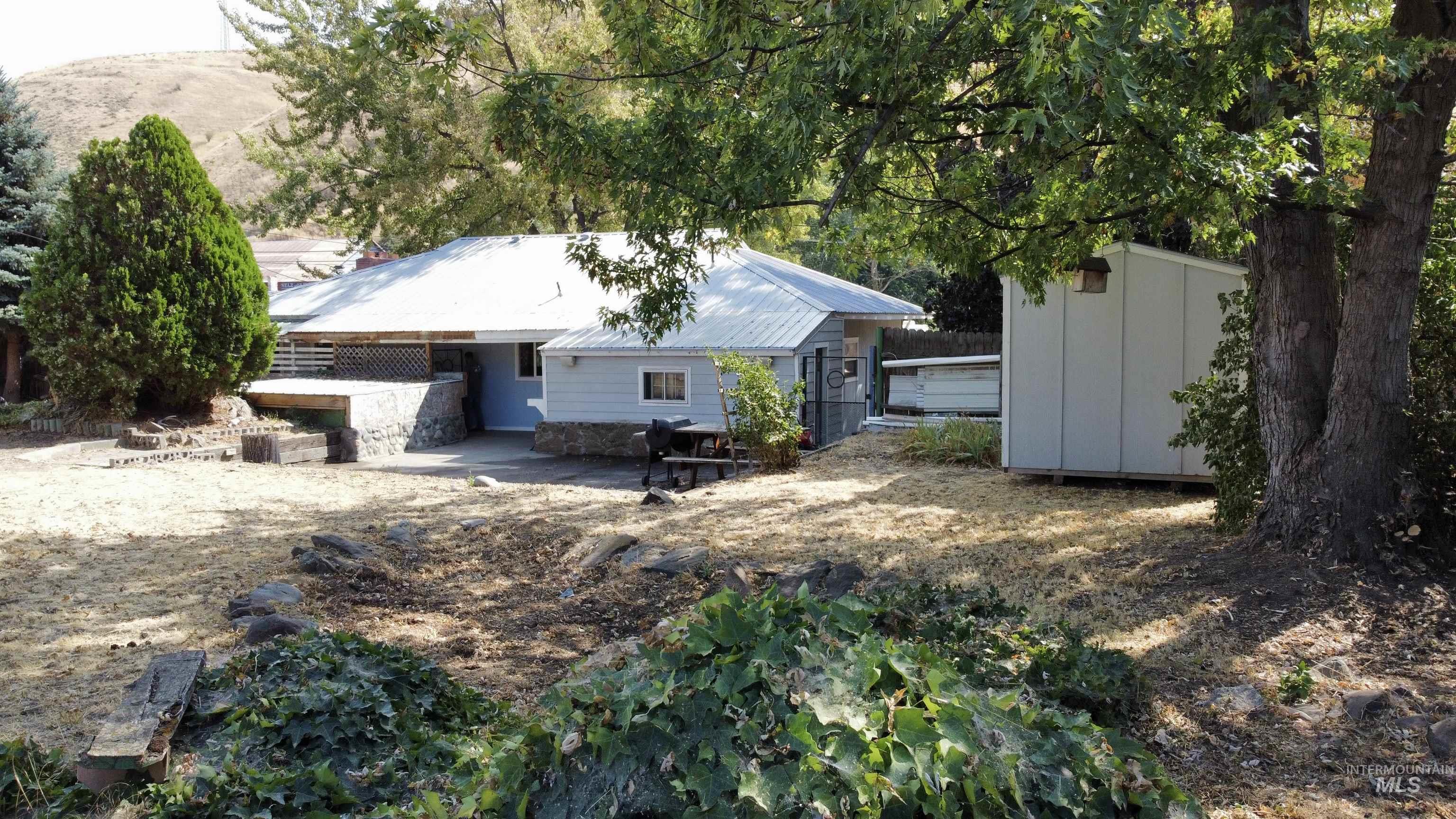 Back of house with a patio, a metal roof, and a storage shed