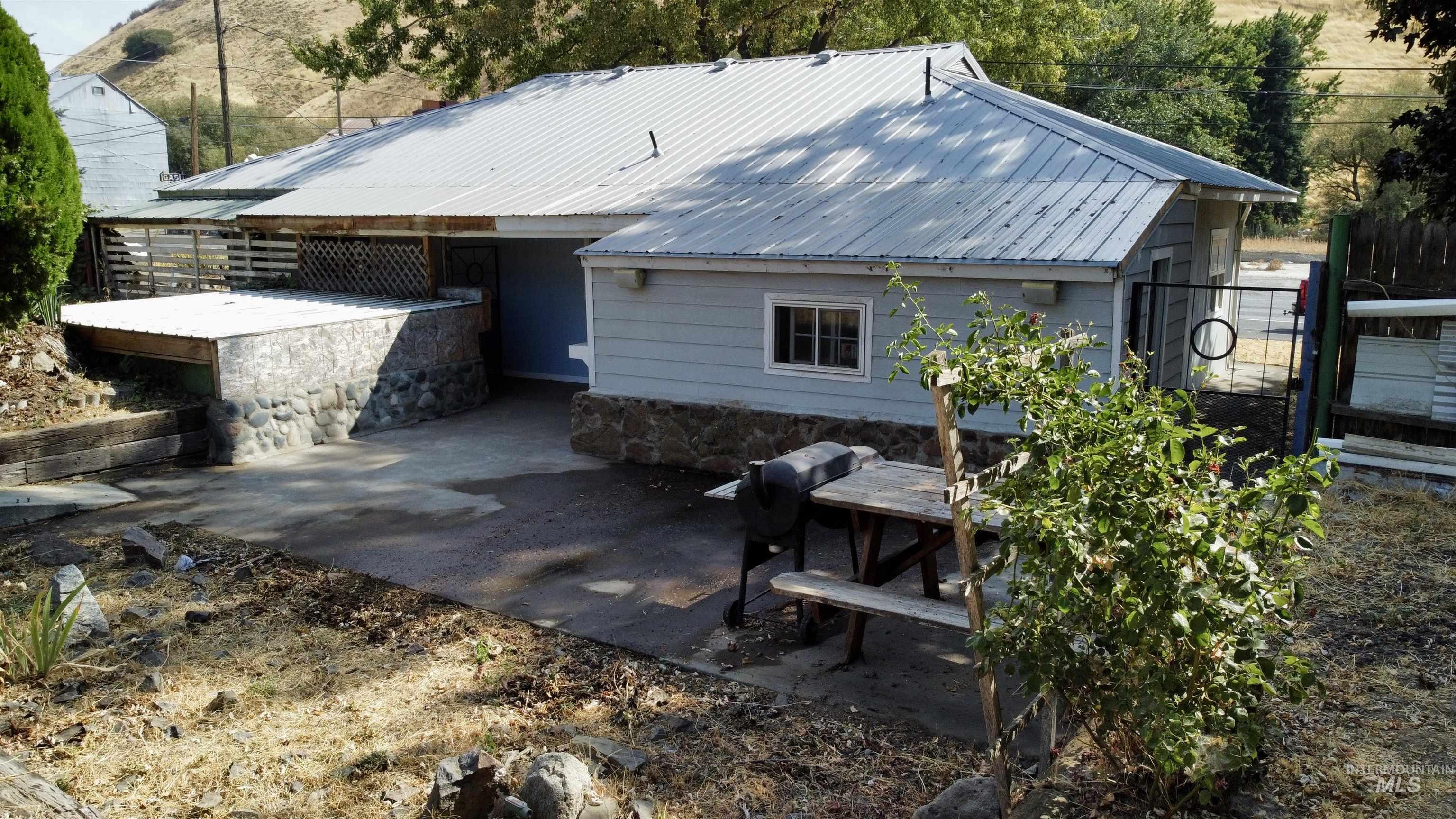 Rear view of property featuring a patio area, a metal roof, and a chimney