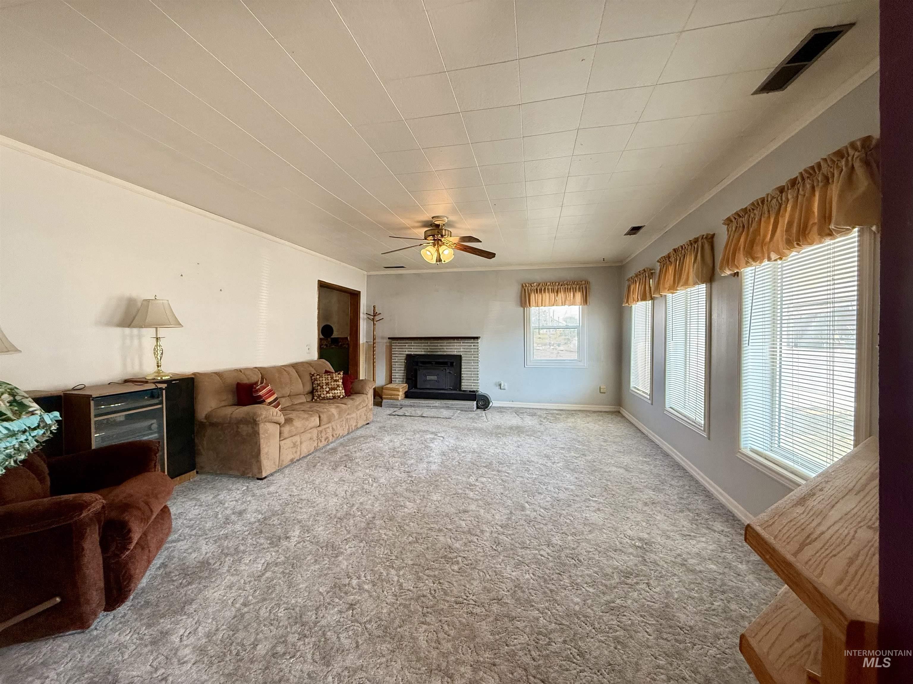 Carpeted living room featuring a ceiling fan and a glass covered fireplace