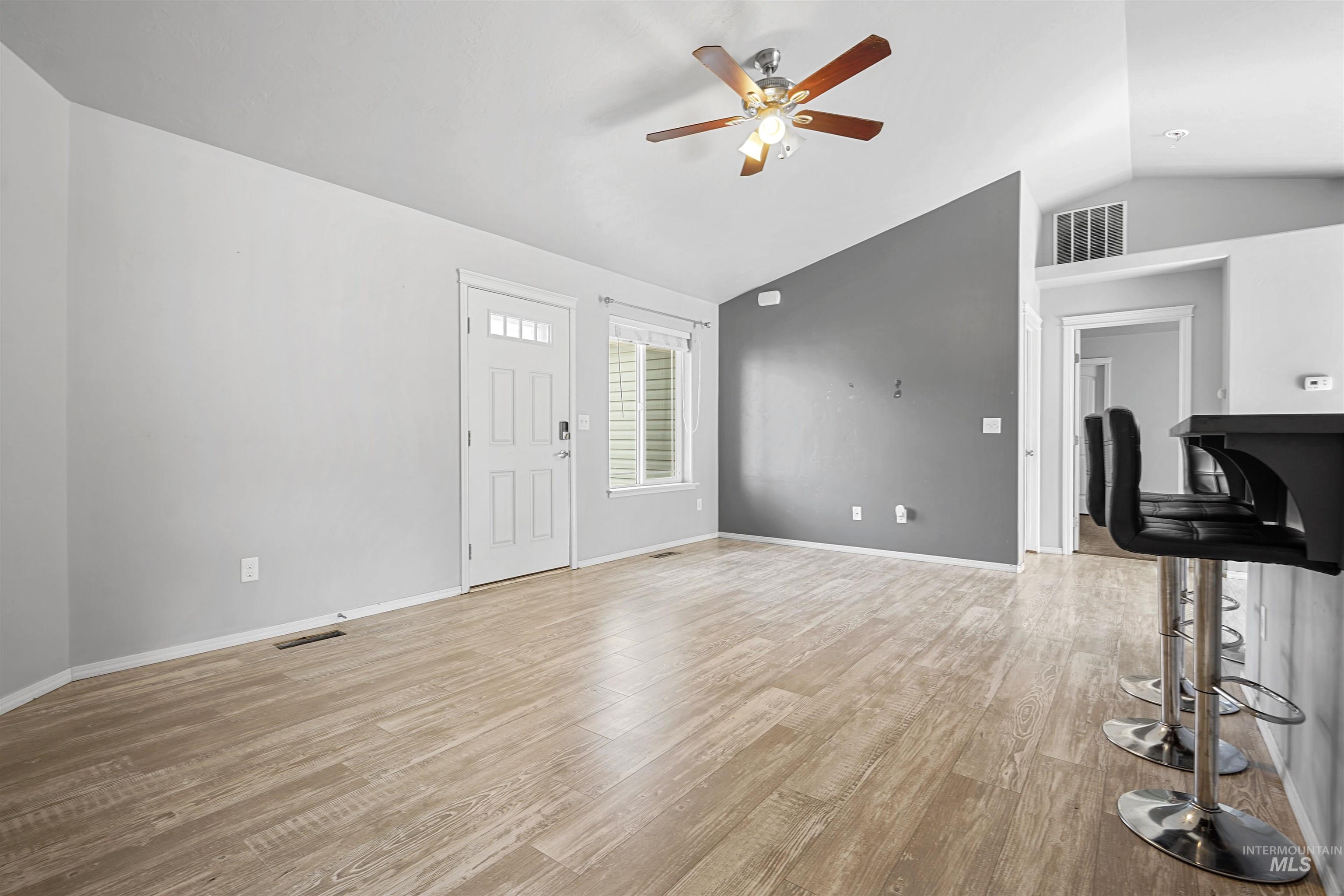 Unfurnished living room with lofted ceiling, light wood-style floors, and ceiling fan