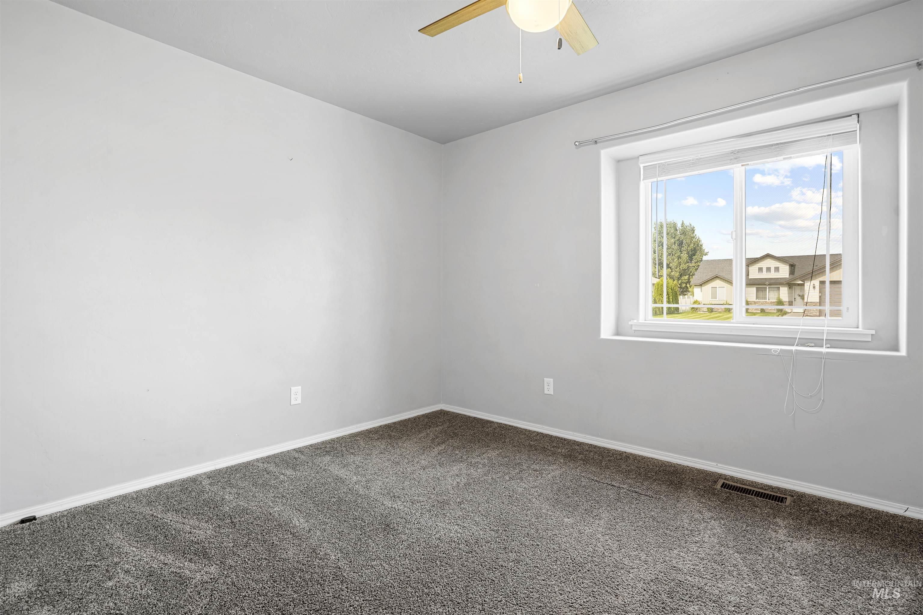 Unfurnished room with dark colored carpet and ceiling fan