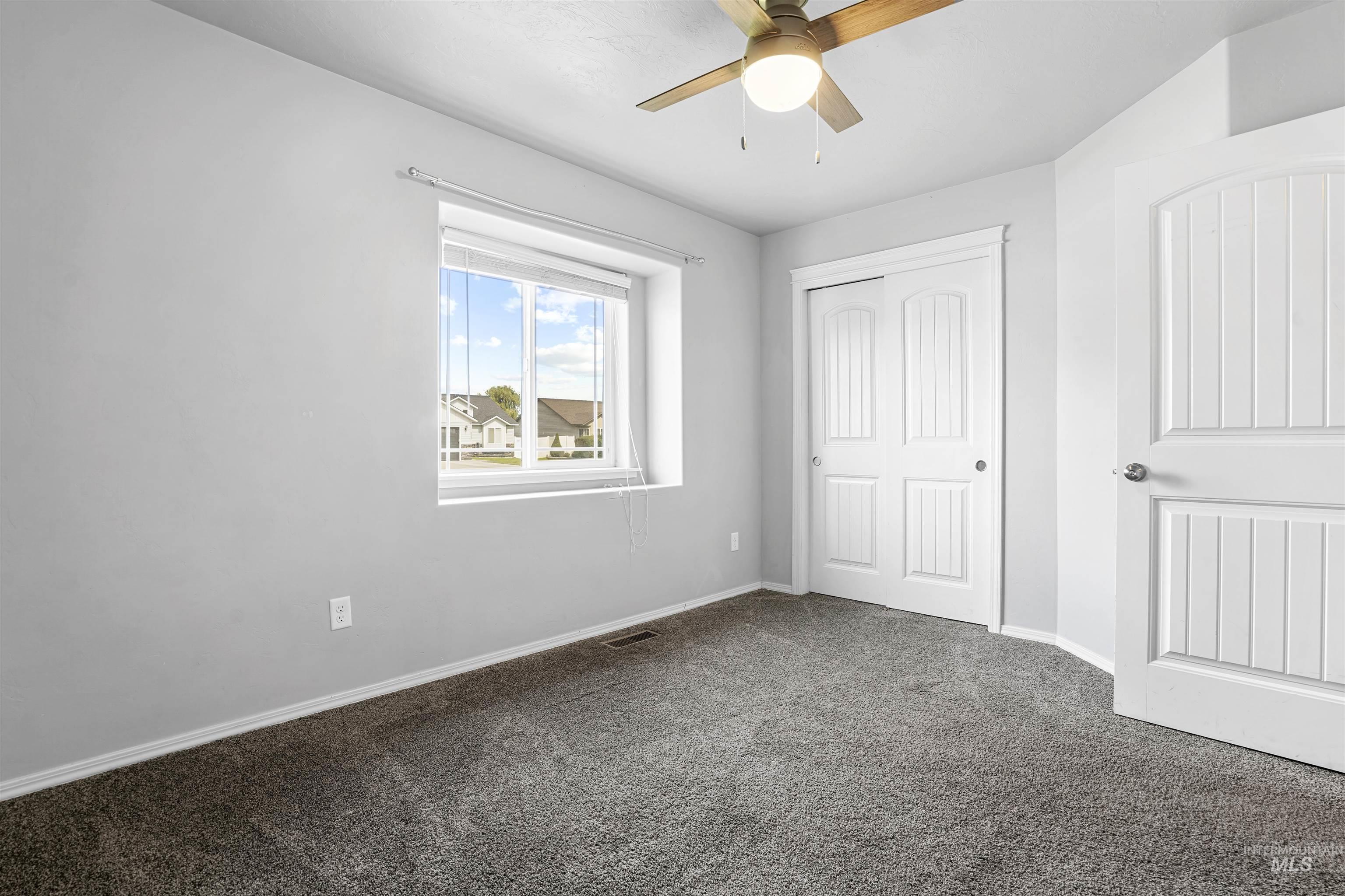 Unfurnished bedroom featuring dark carpet, a closet, and ceiling fan