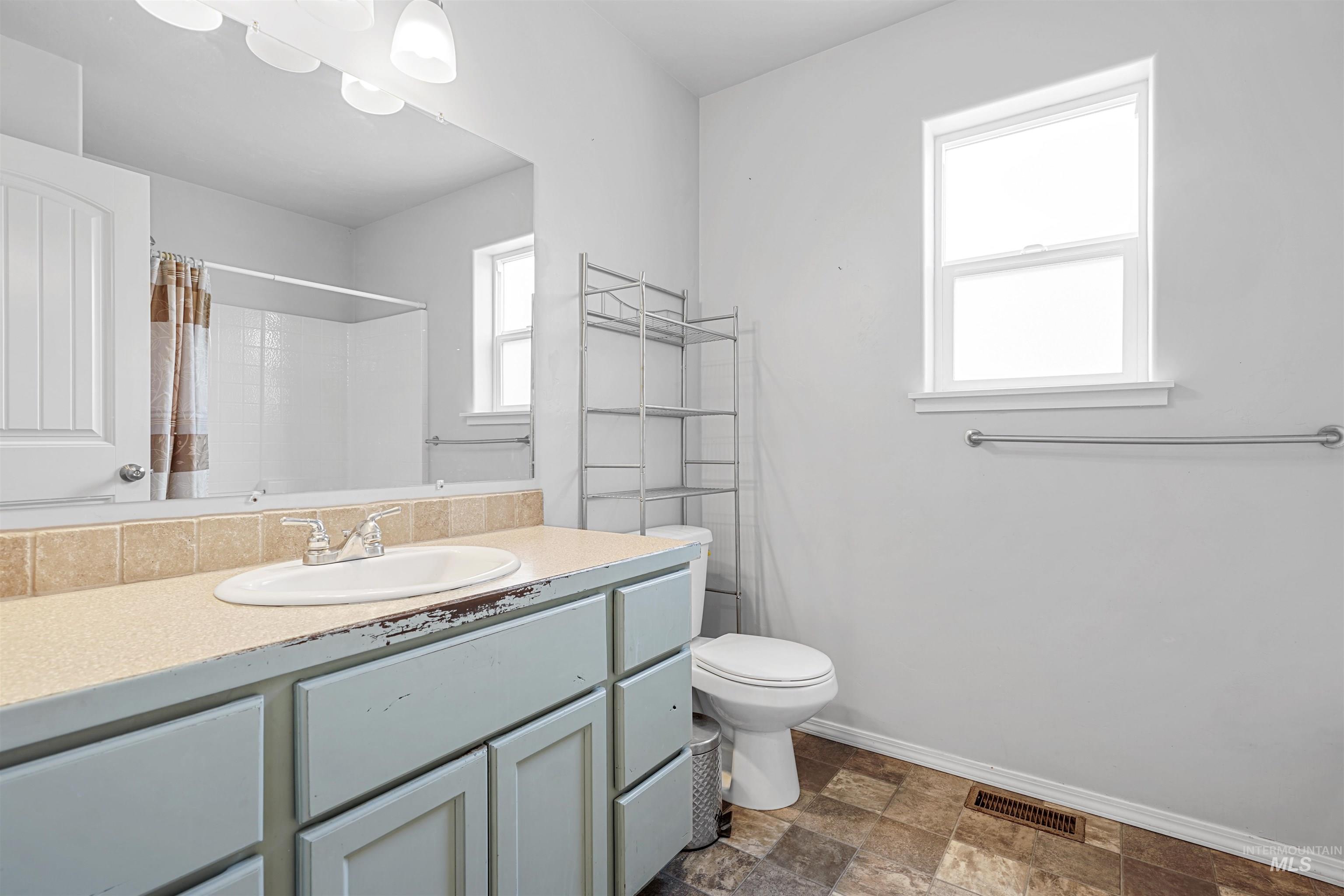 Bathroom with vanity, stone finish flooring, and a shower with shower curtain