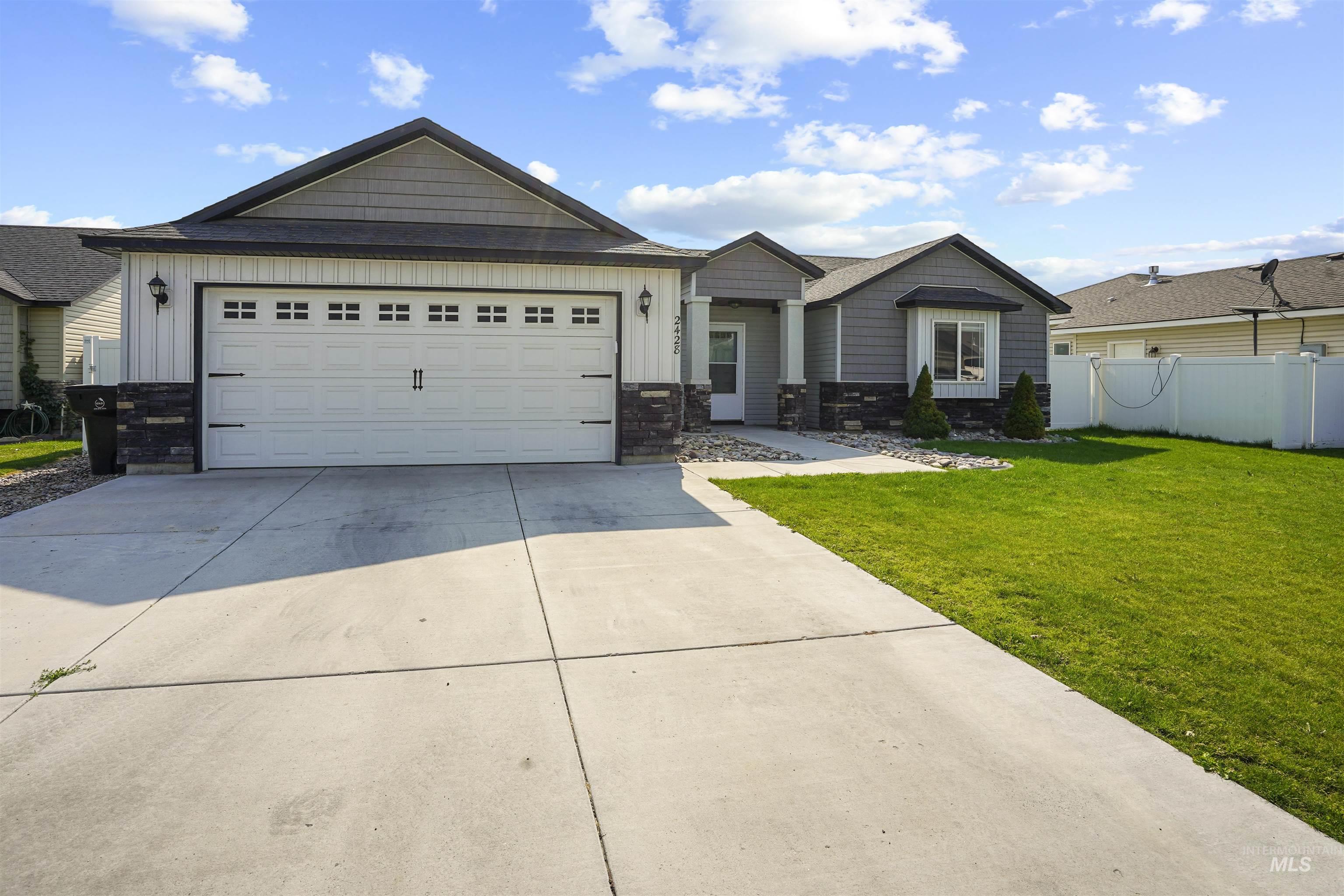 View of front of house featuring board and batten siding, driveway, an attached garage, and stone siding